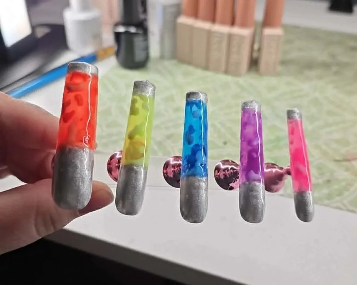 Colorful glass marbles with red, yellow, blue, purple, and pink colors, set on a transparent stand.