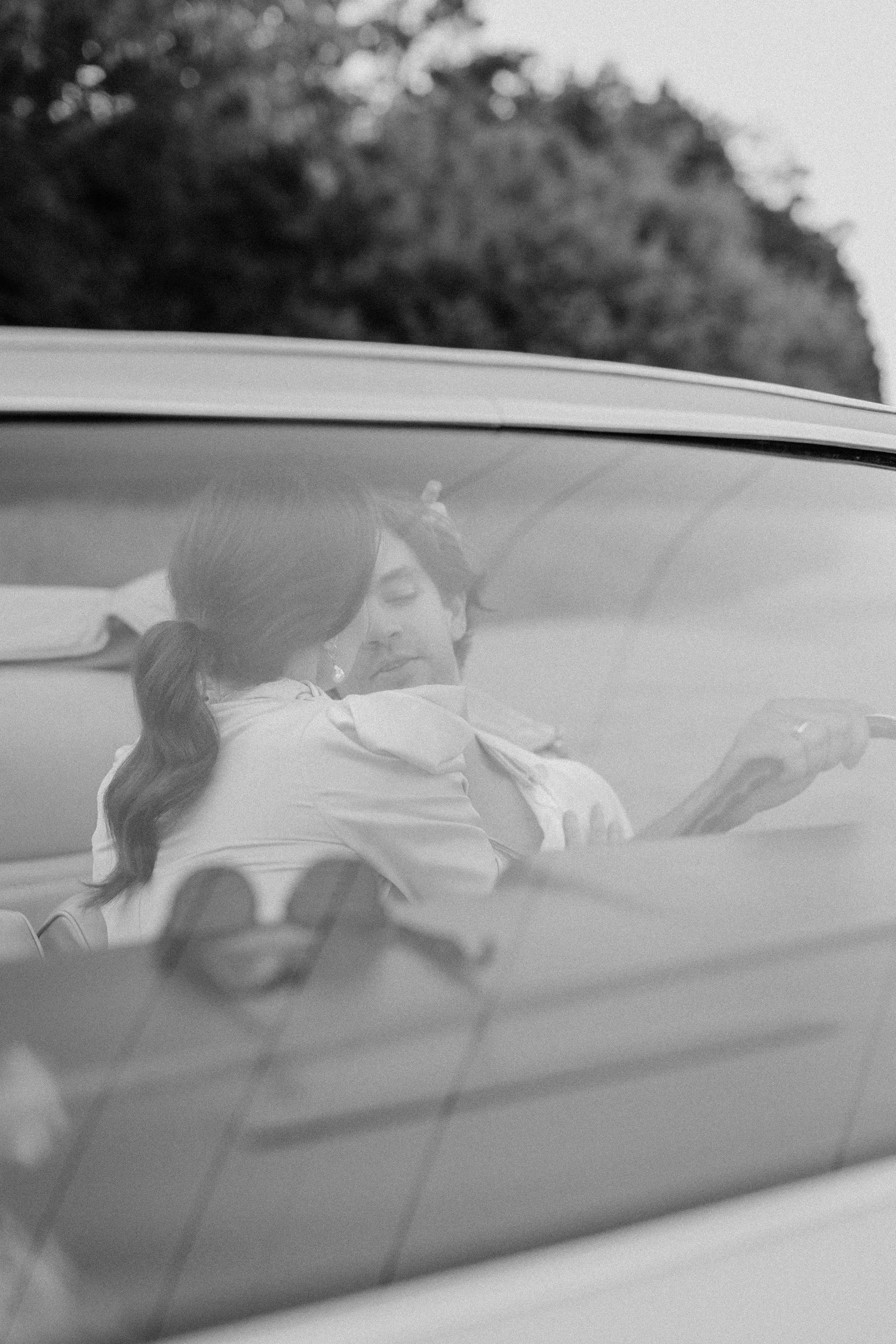 Wedding Website Design, Digital Wedding Stationery, Web Design and Branding for Wedding Professionals | Avelã White. Black and white photo of two people sitting in a car, seemingly kissing.