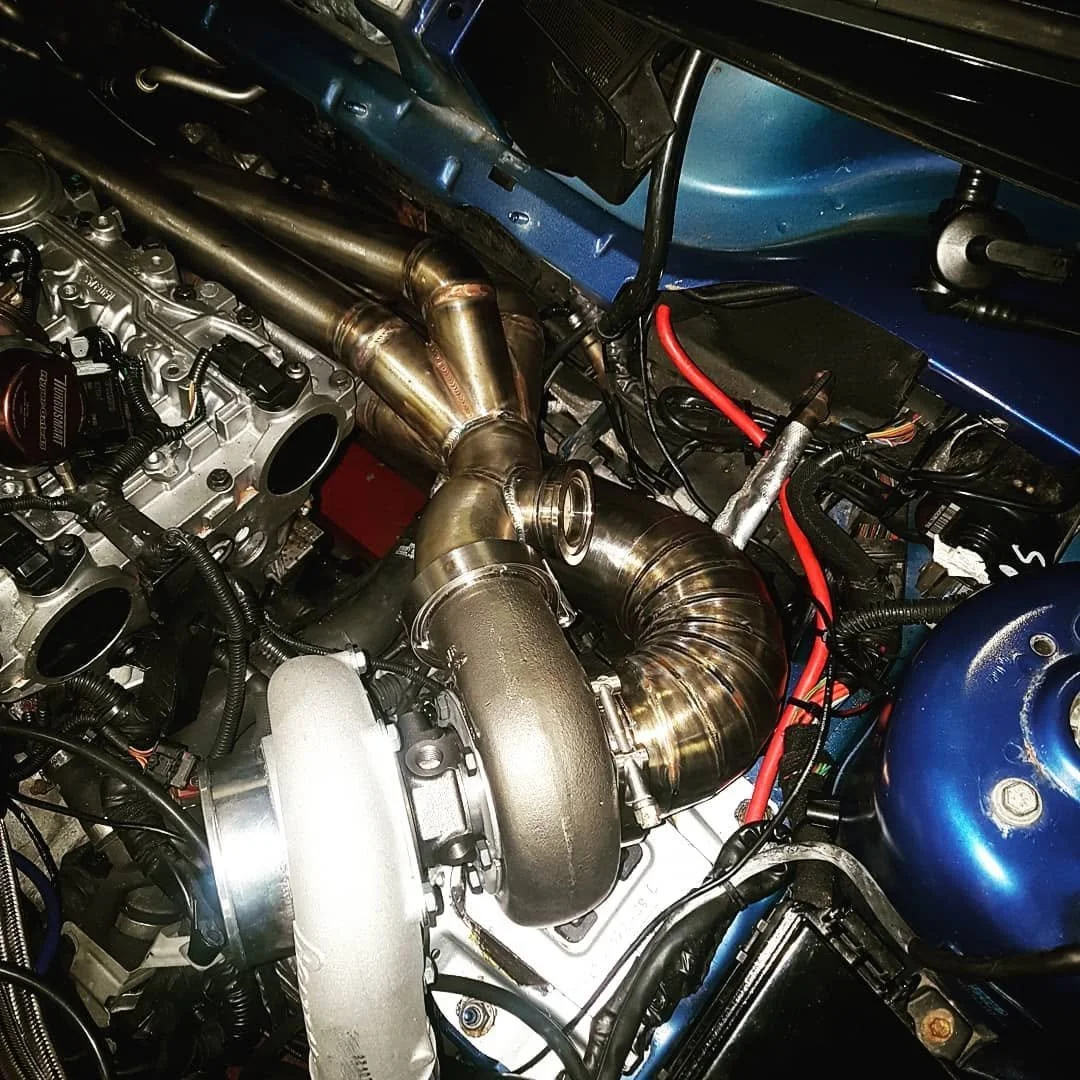 Close-up of a car engine with a large, shiny turbocharger and an exhaust manifold.