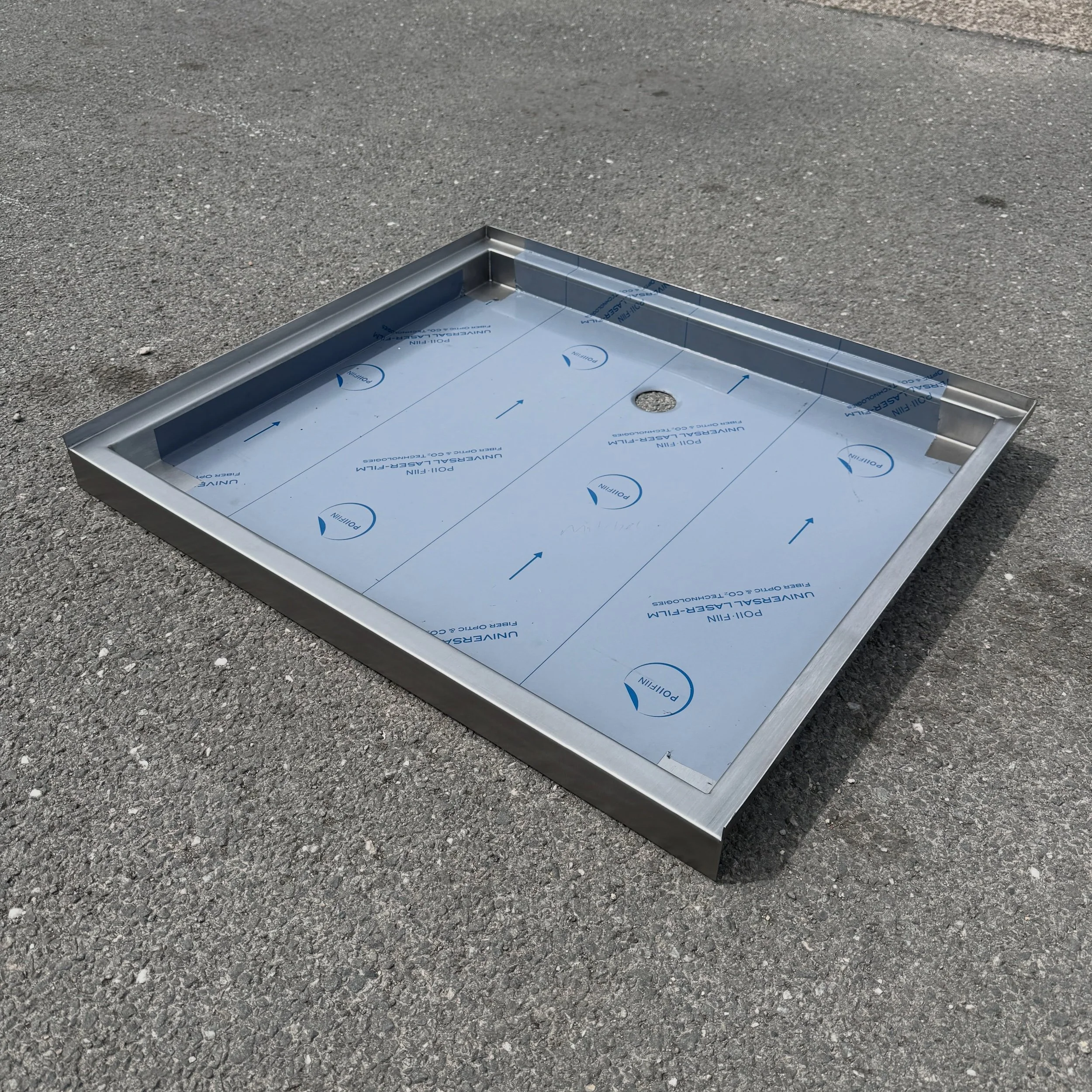 Close-up of a metal roof flashing on asphalt pavement, with construction paper underneath.