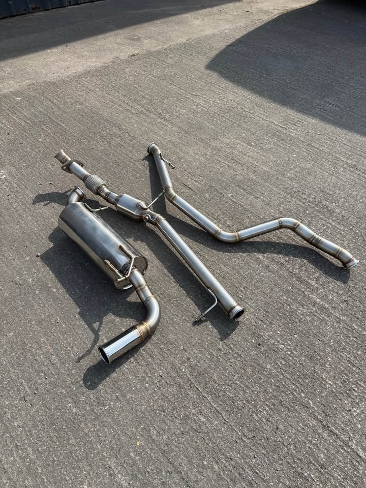 Car exhaust system laid out on asphalt ground.