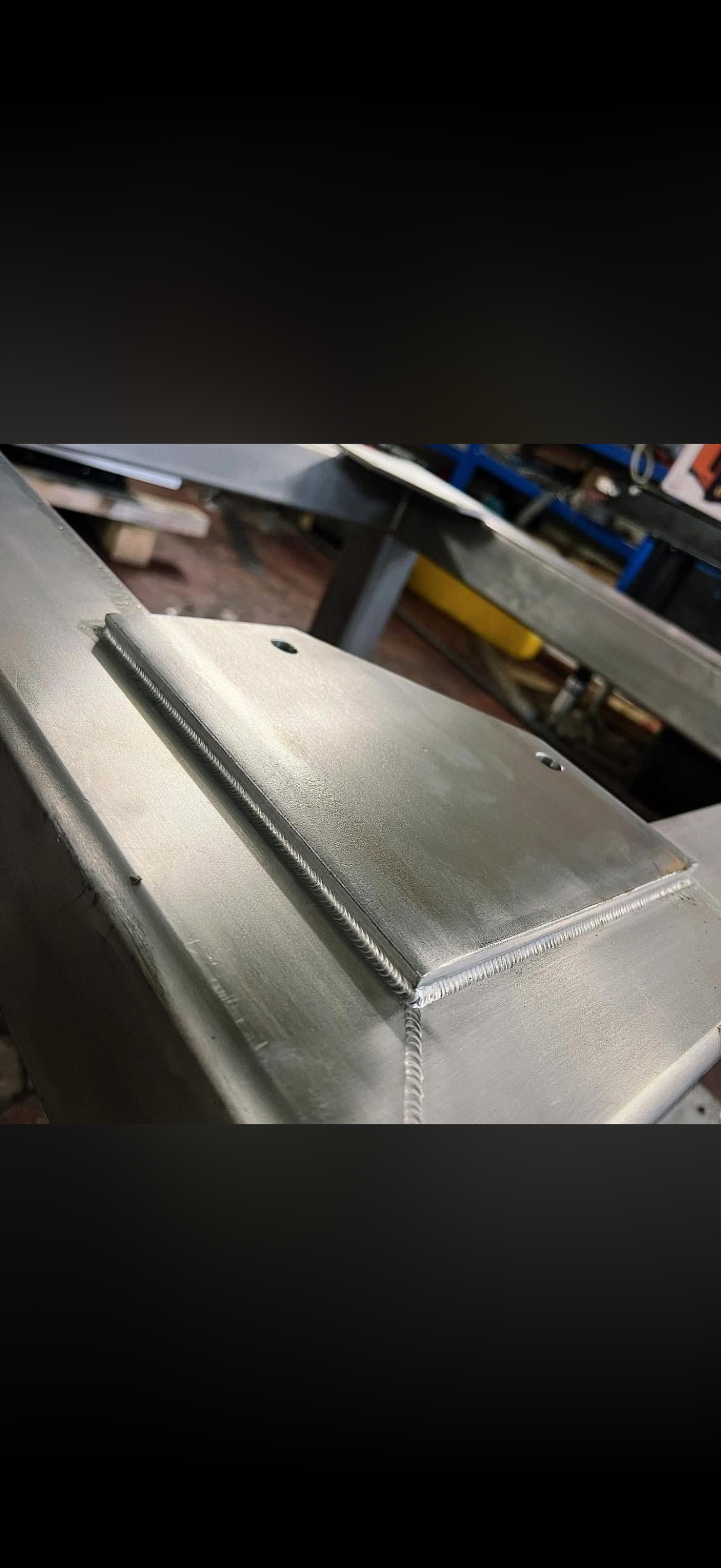 Close-up of a metal part with welded joints, on a workbench in a workshop.
