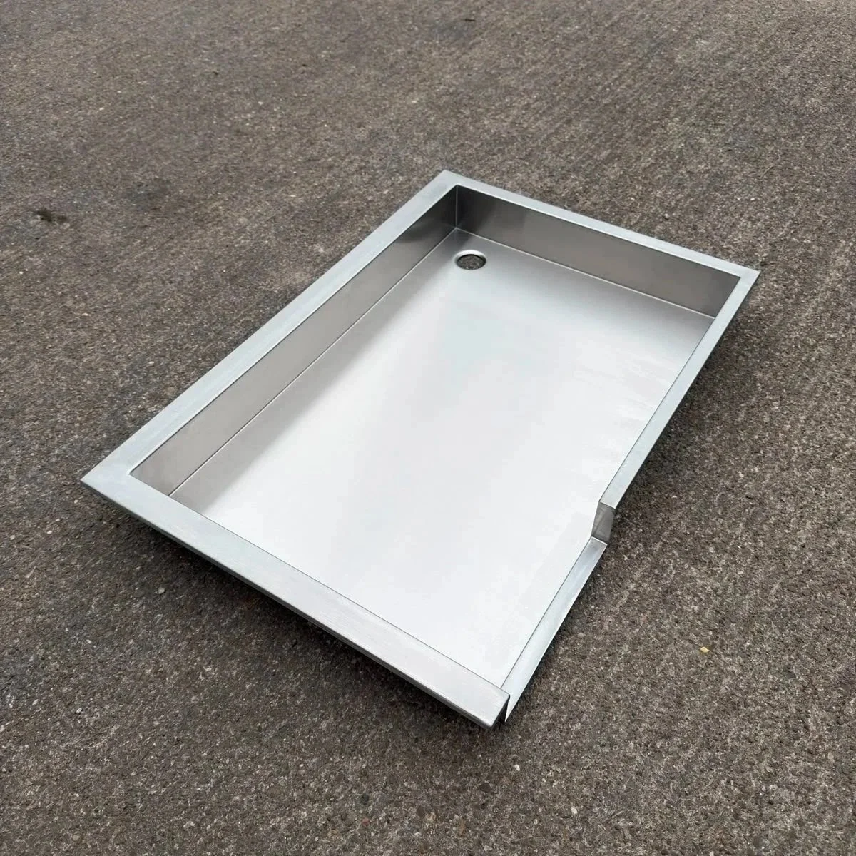 Stainless steel shower base on concrete ground.
