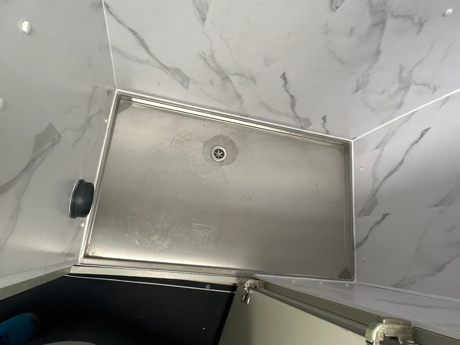 camper van Shower tray with marble wall tiles, metal drain