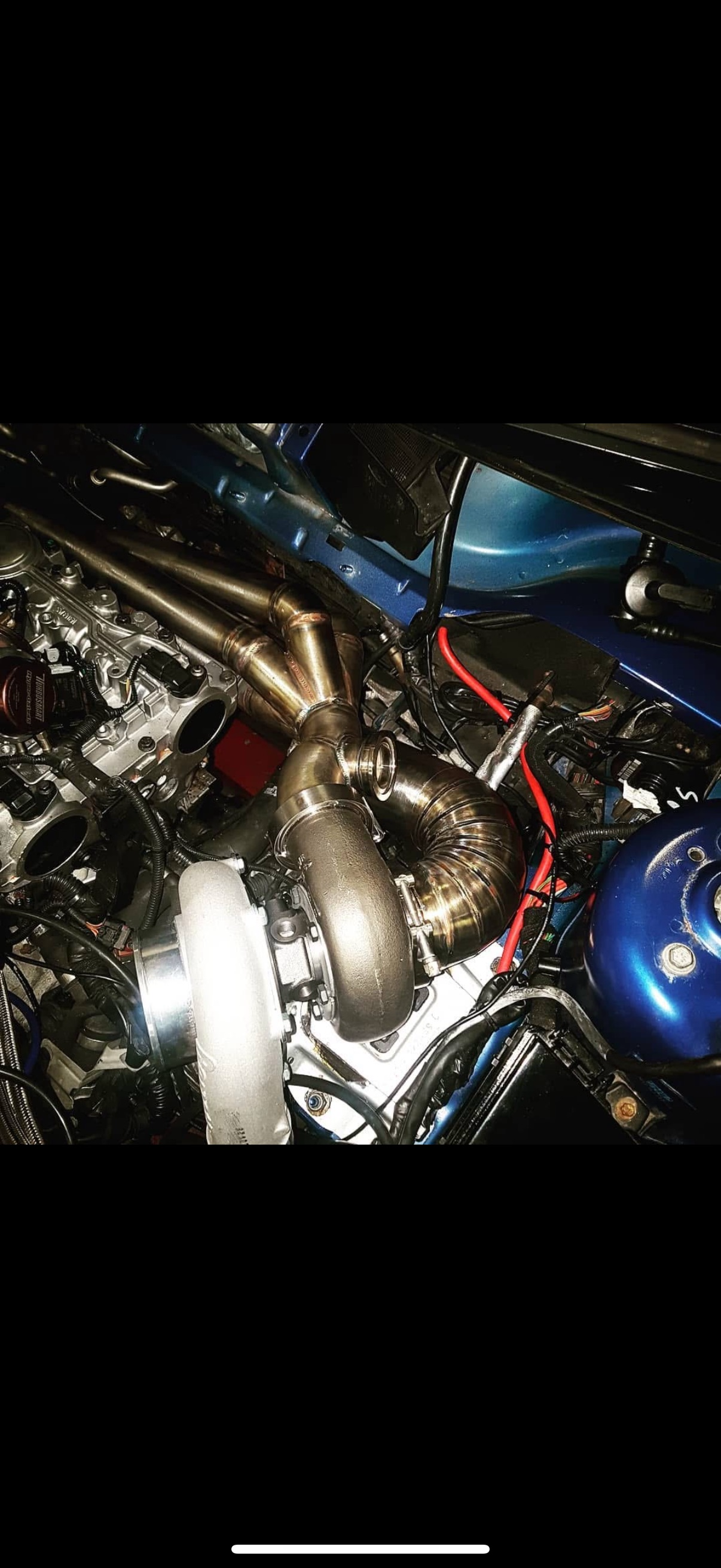 Close-up of a car engine with a large turbocharger, engine components, and wiring visible.