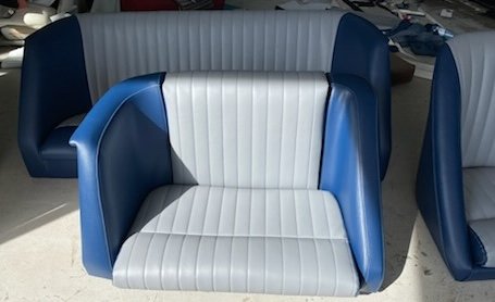 A blue and white retro-style armchair with curved sides and vertical stripe upholstery in a room with other furniture.