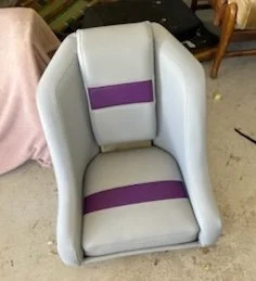 A gray and purple upholstered armchair with a high back and armrests in a room.