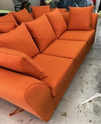 Orange sofa with multiple cushions in a room.
