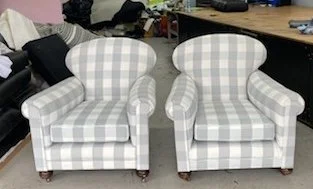 Two plaid upholstered armchairs with rounded backs and arms in a room with a desk and other furniture.