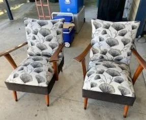 Two patterned armchairs with wooden arms and dark legs, placed outdoors on a concrete surface.