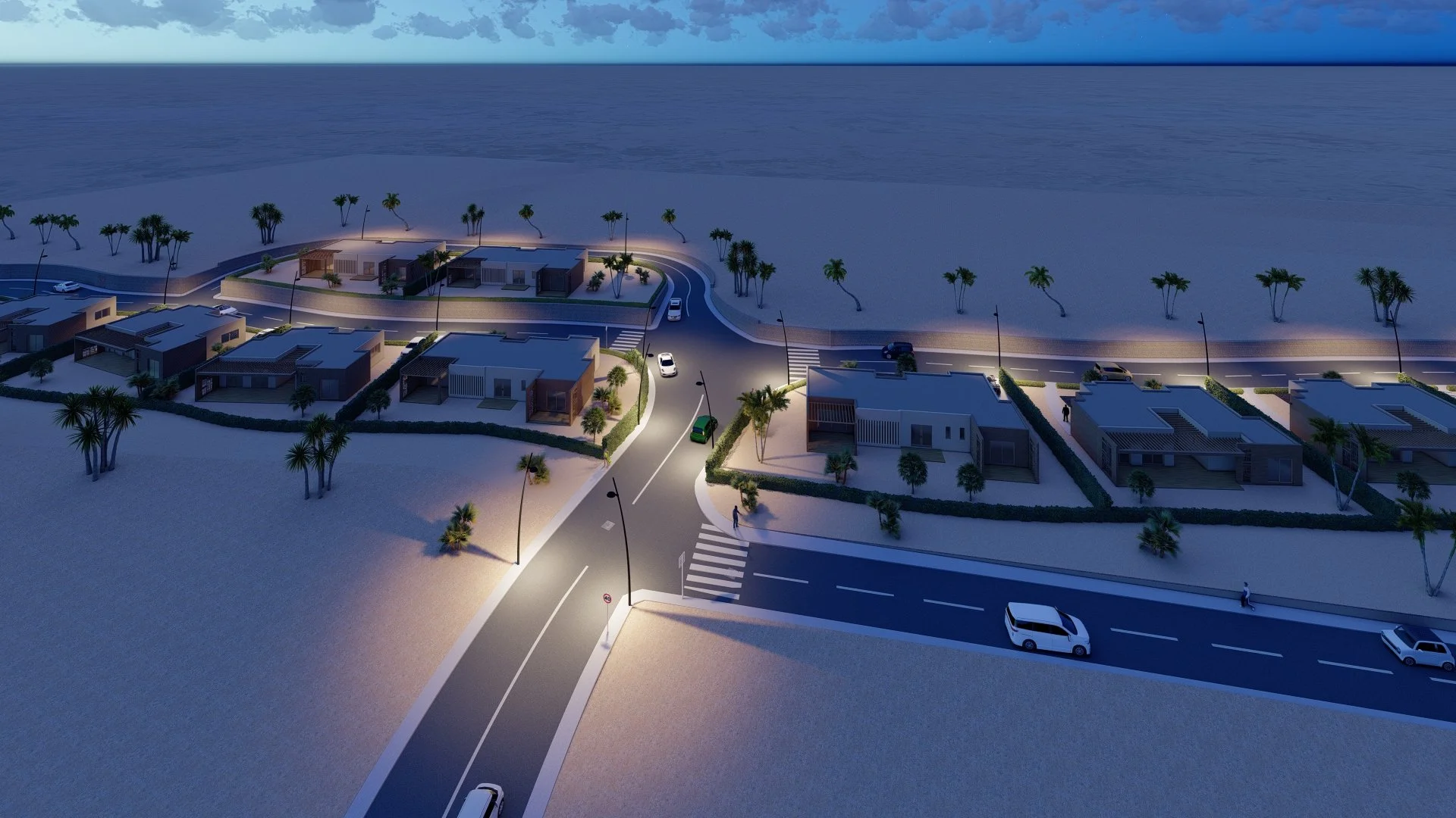 Vue aérienne d'un lotissement résidentiel en soirée, avec des maisons modernes, des routes, des lampadaires allumés, des palmiers et la mer en arrière-plan.