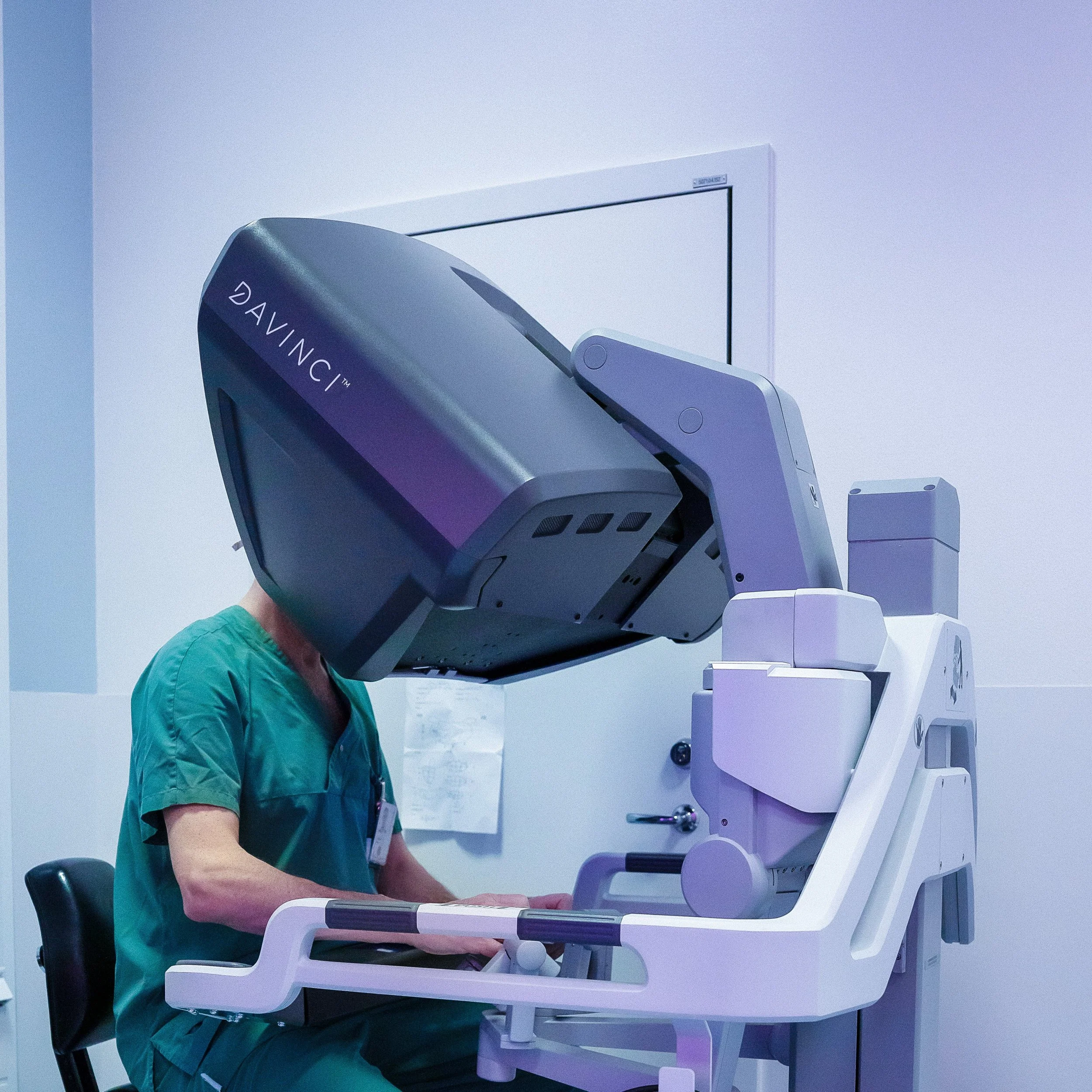 Doctor or medical technician using a large surgical or diagnostic imaging machine in a clinical setting.