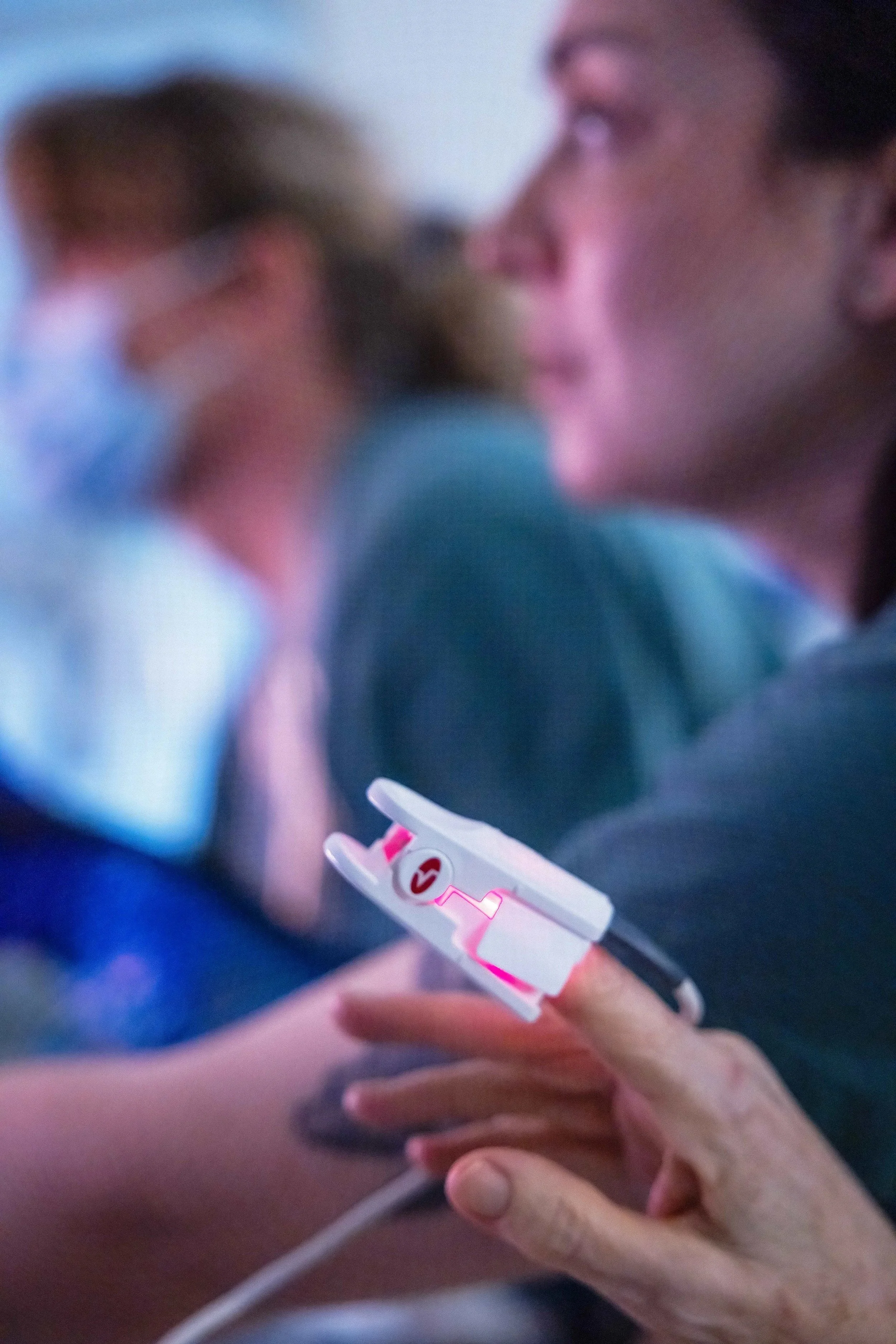 Close-up of a healthcare professional's hand holding a syringe with a pink needle, preparing to administer an injection to a patient's arm.