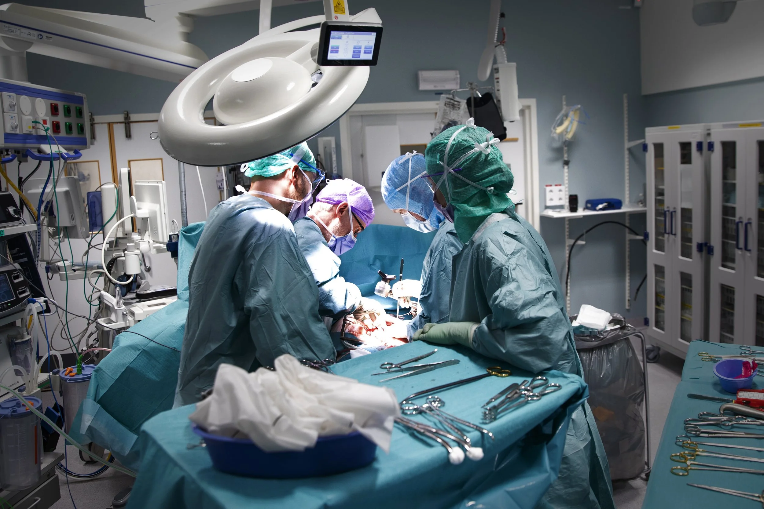 A team of surgeons performing surgery in an operating room with surgical instruments and medical equipment.