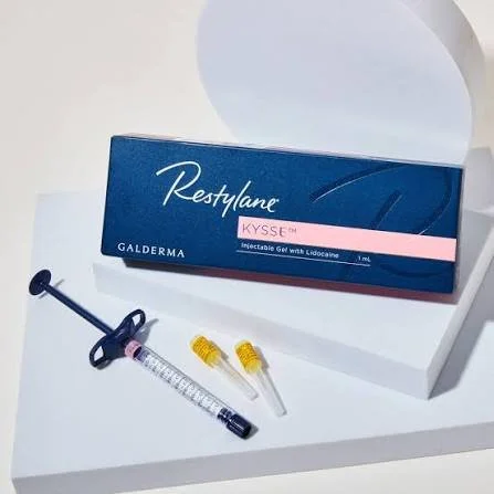 Box of Restylane KYSSÉ dermal filler product, syringe, and two small vials on a white surface.