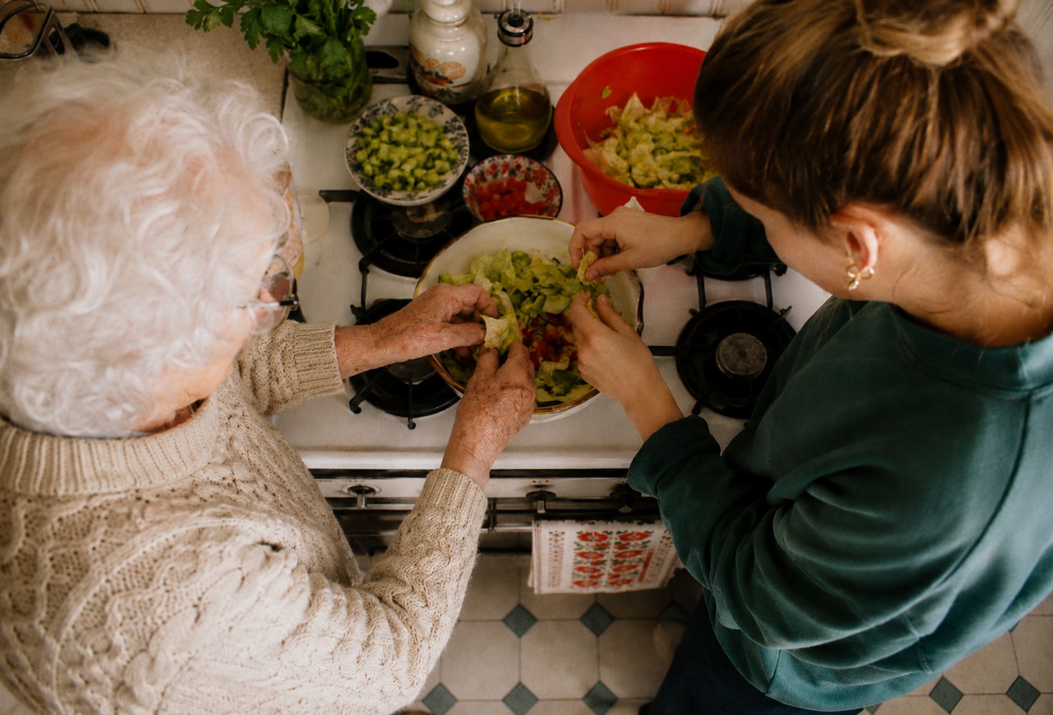 Eine ältere Frau und eine jüngere Frau bereiten einen Salat mit frischem Gemüse in der Küche vor.