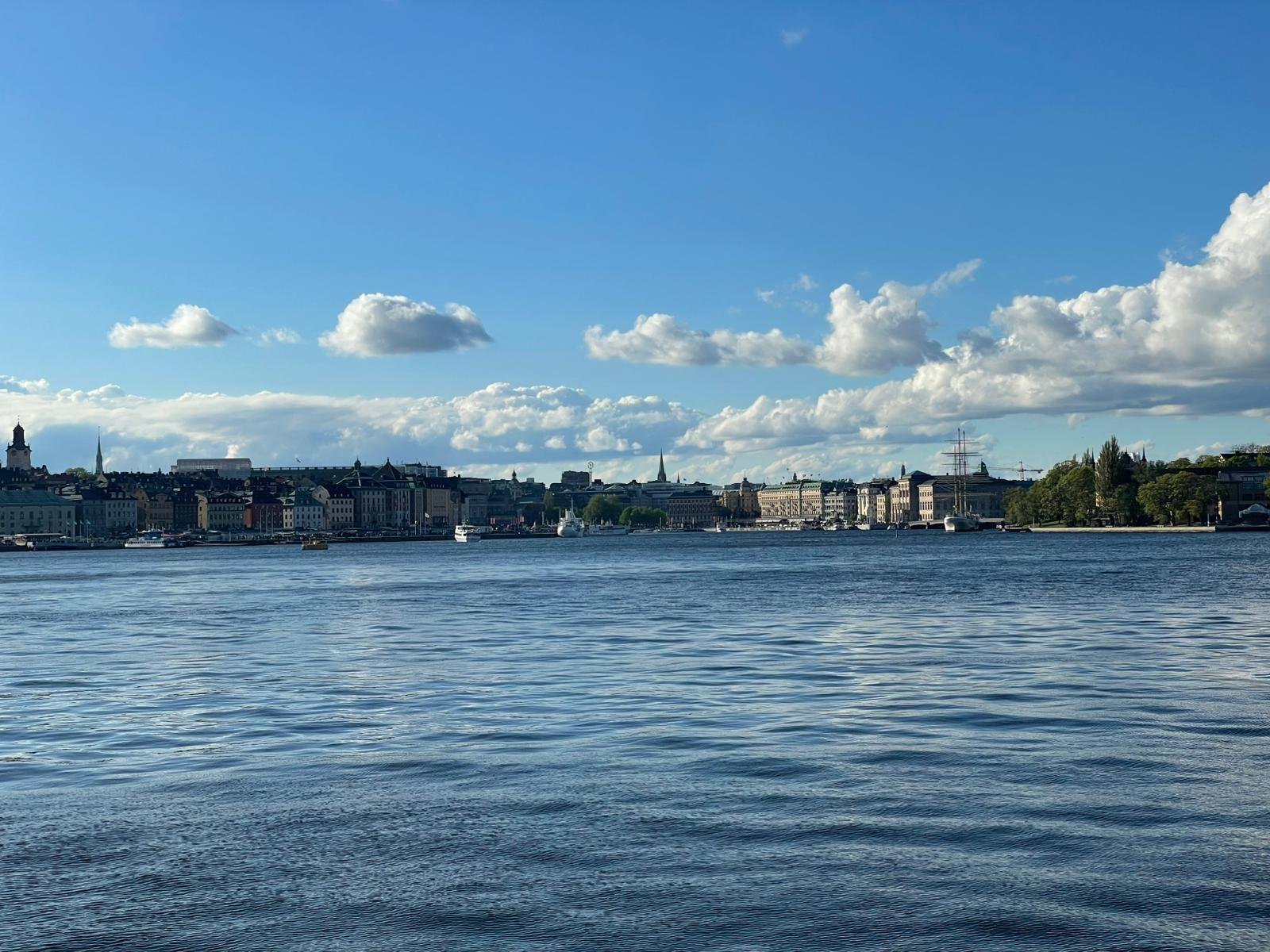Vanaf het water kijk je naar de Stockholm skyline op een mooie dag met heldere lucht en wolkjes.