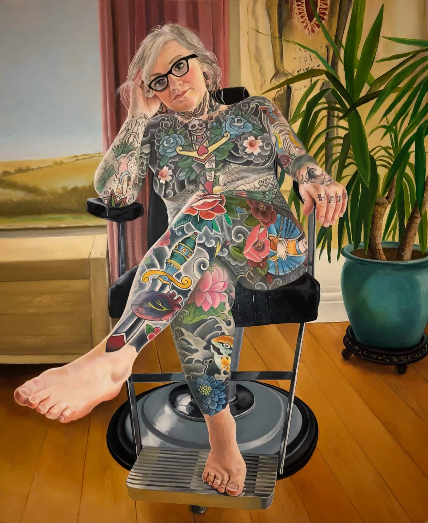 A heavily tattooed woman with gray hair and glasses sitting in an old fashioned dentist chair with a large potted plant nearby.