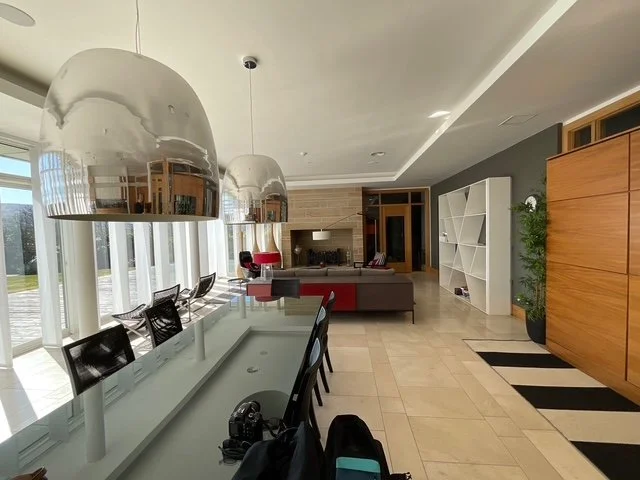 Spacious living room and dining area with large windows, modern pendant lights, and contemporary furniture.