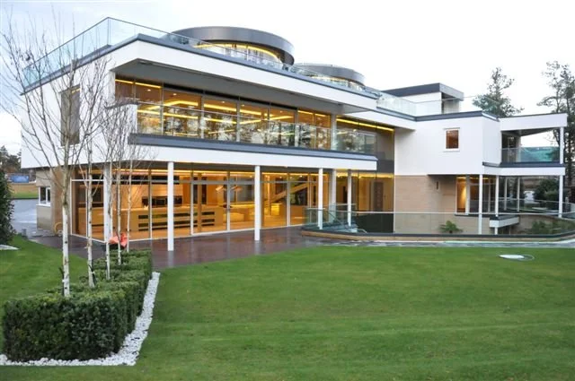 Modernist House with large glass windows, surrounded by a well-maintained lawn and landscaped yard.