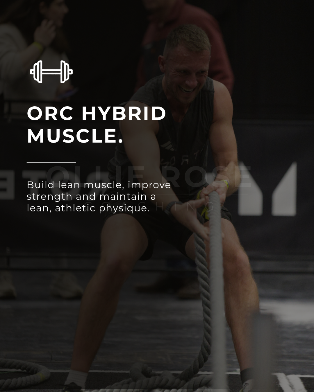 A man smiling while pulling on battle ropes during a workout at a gym.