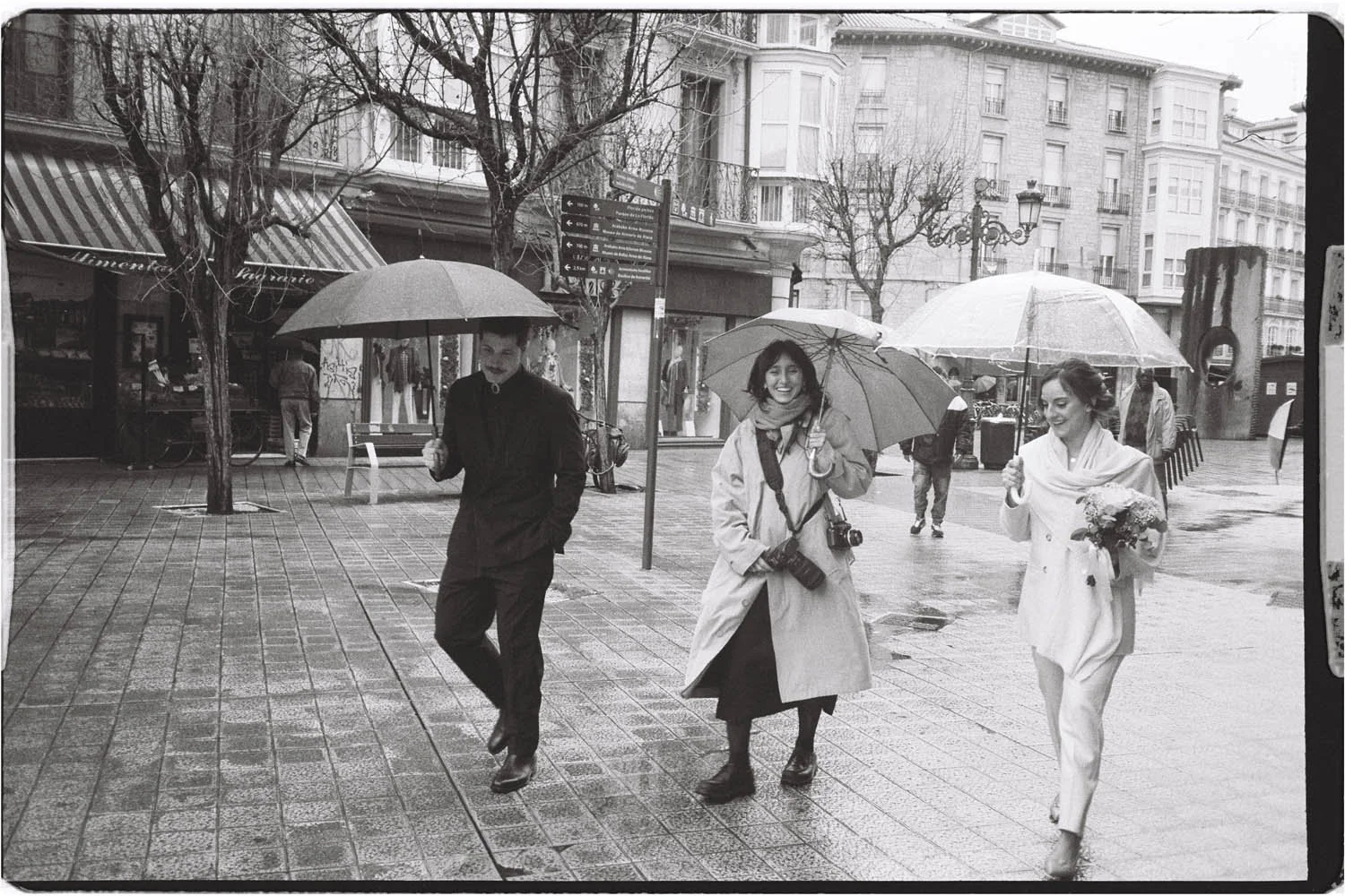 wedding photographer walking with couple under the rain