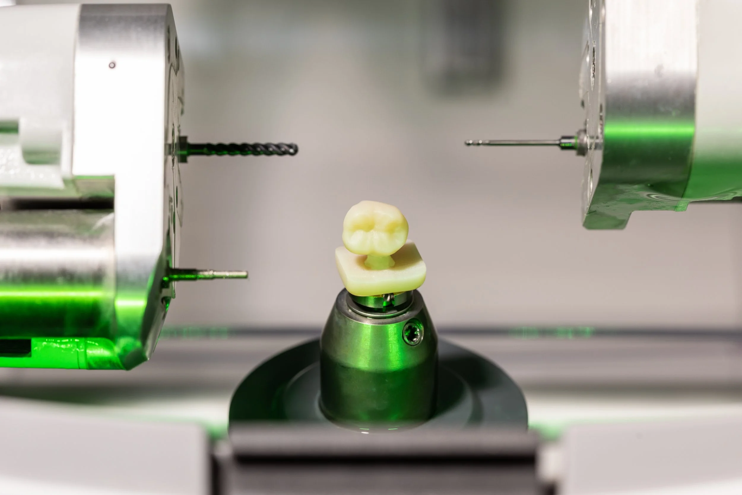 A dental milling machine with a computer-aided design model of a tooth, showing the device in operation.
