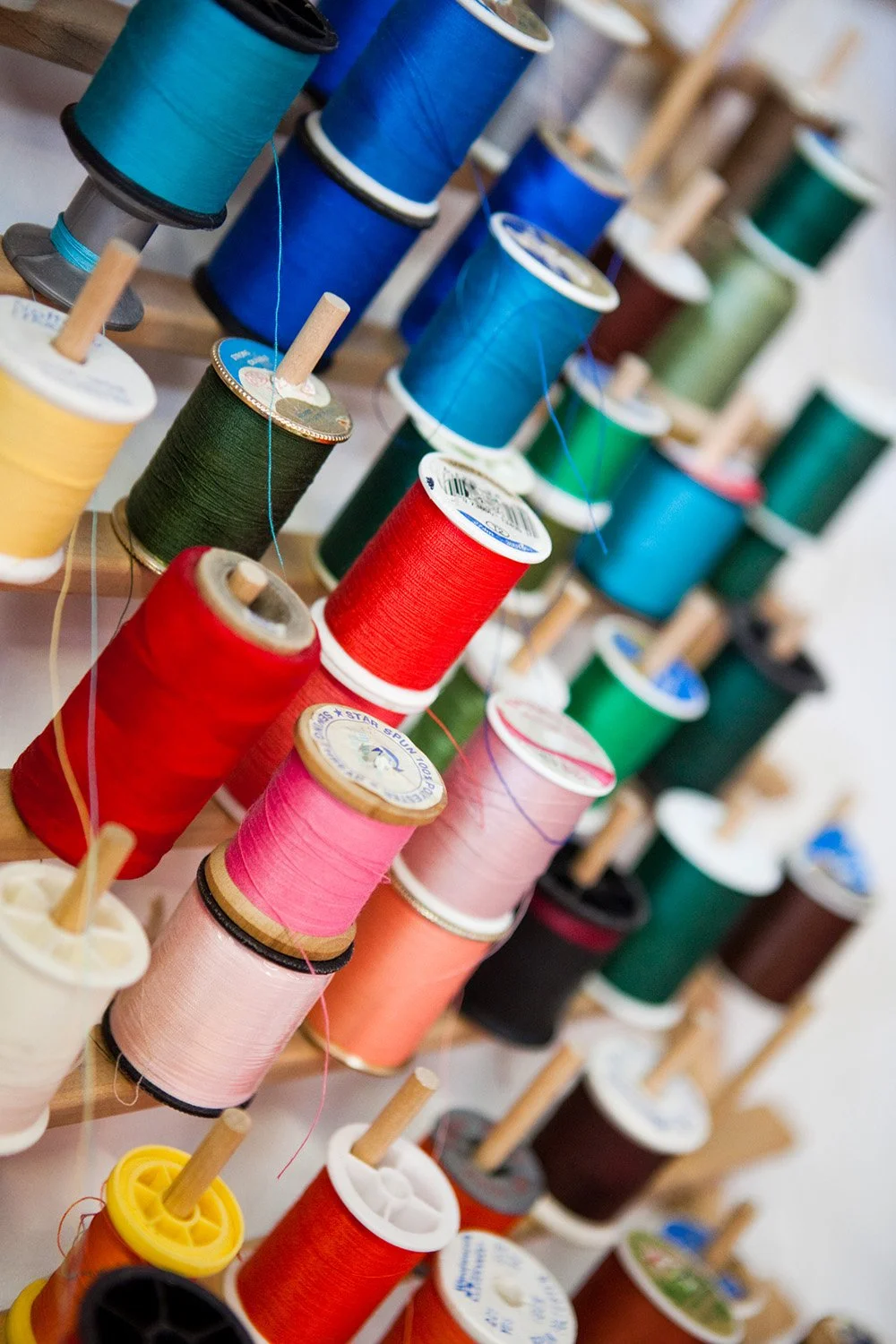 Spools of colorful thread on wooden racks.