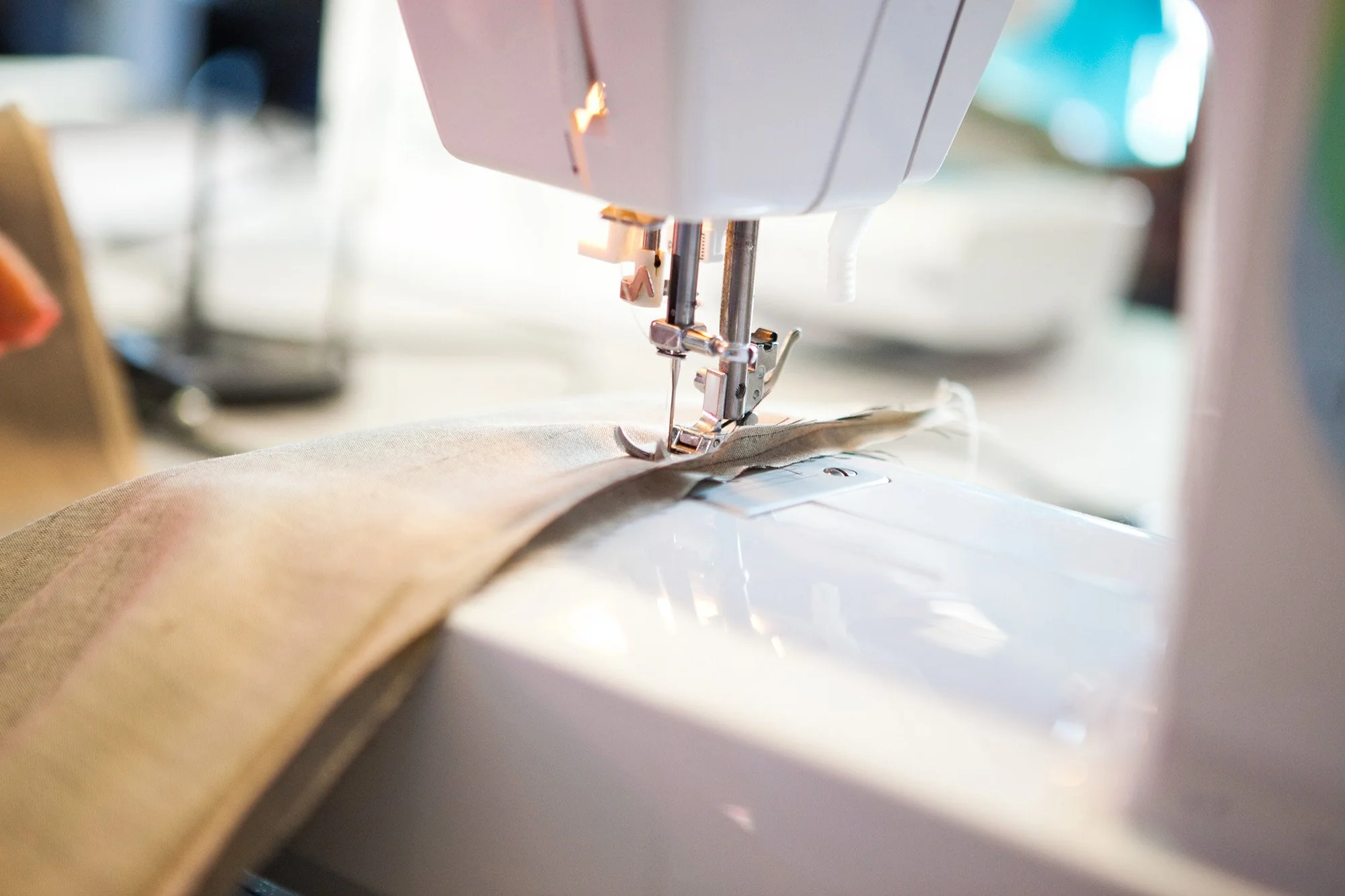 A close-up view of a sewing machine needle stitching fabric.