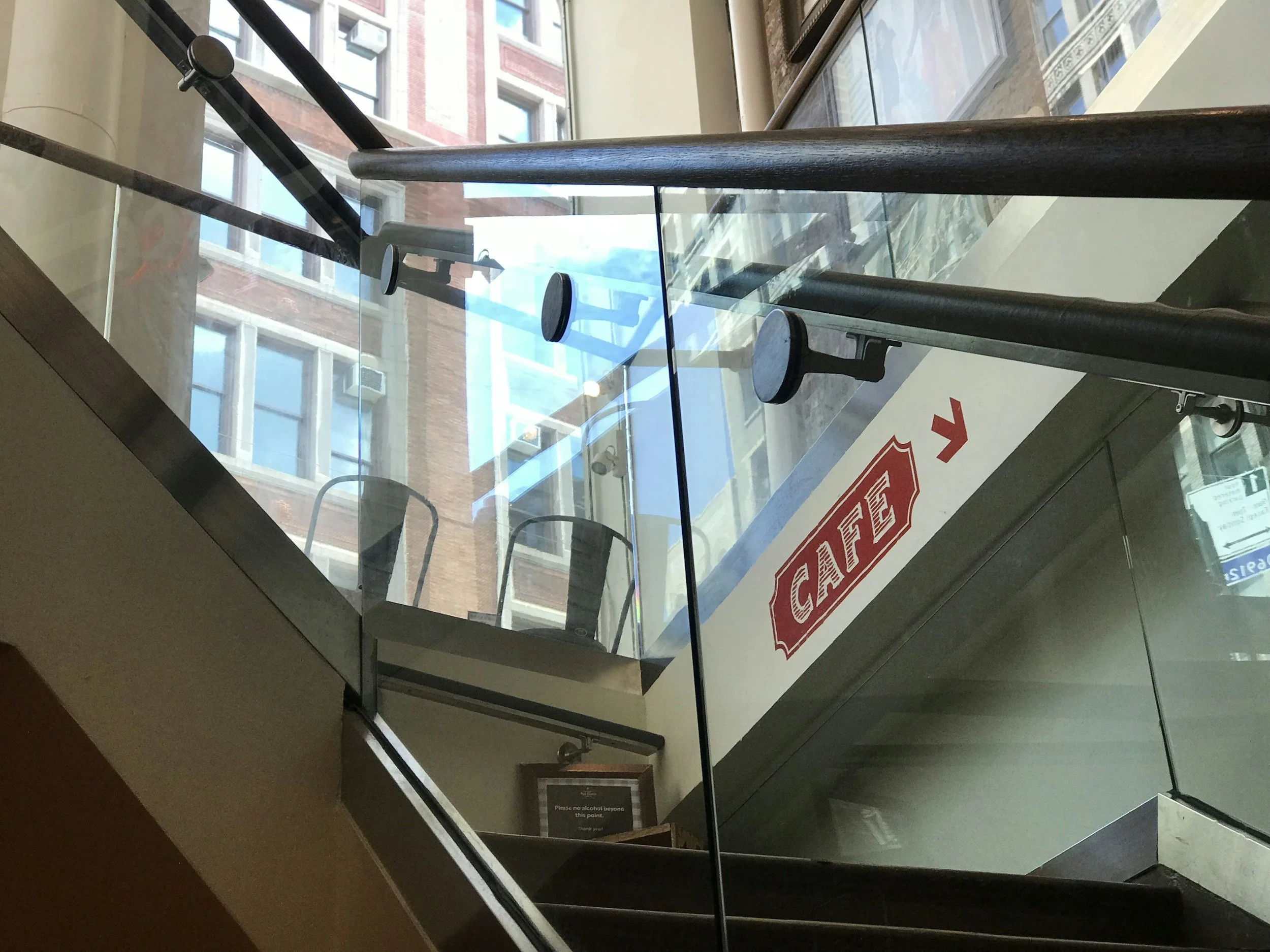 View of a glass staircase and large windows with a red building visible outside.