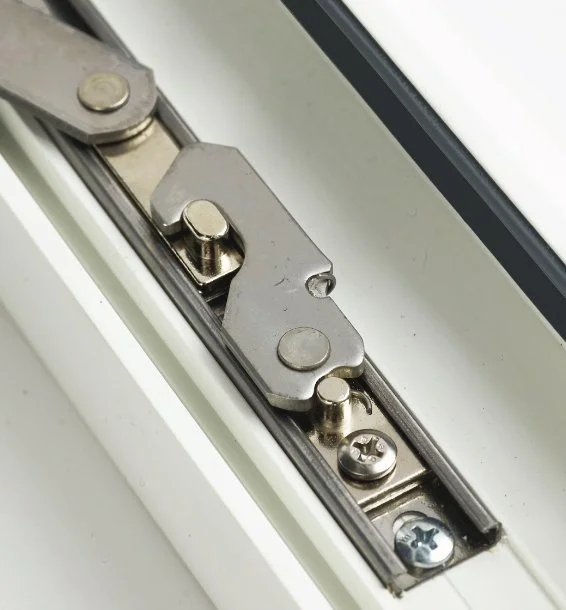 Close-up of a window lock and latch mechanism on a white window frame.