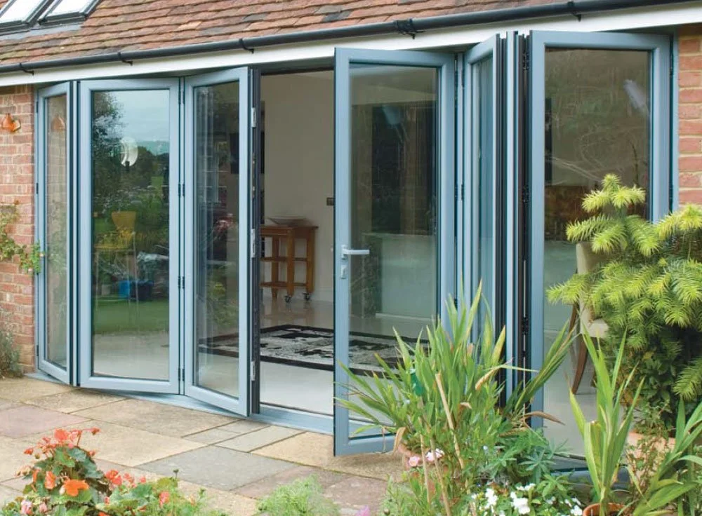 Home with expanding glass patio door, brick exterior, outdoor plants and flowers, patio tiles