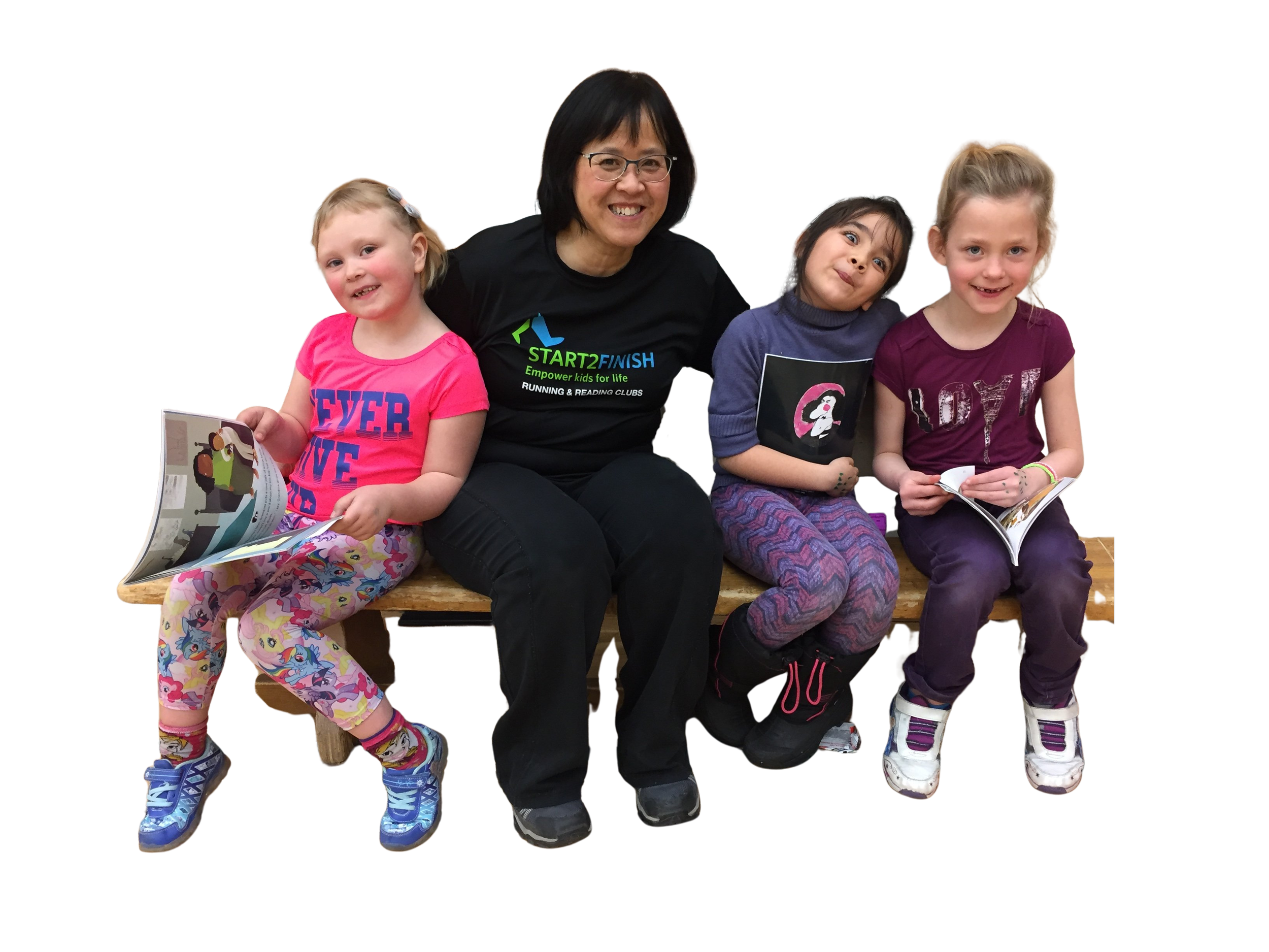 A group of four children and an adult woman sitting on a wooden bench, reading books, smiling, and posing for the photo. The children are wearing colorful clothing and sneakers, and the woman is dressed in a black shirt with a logo.