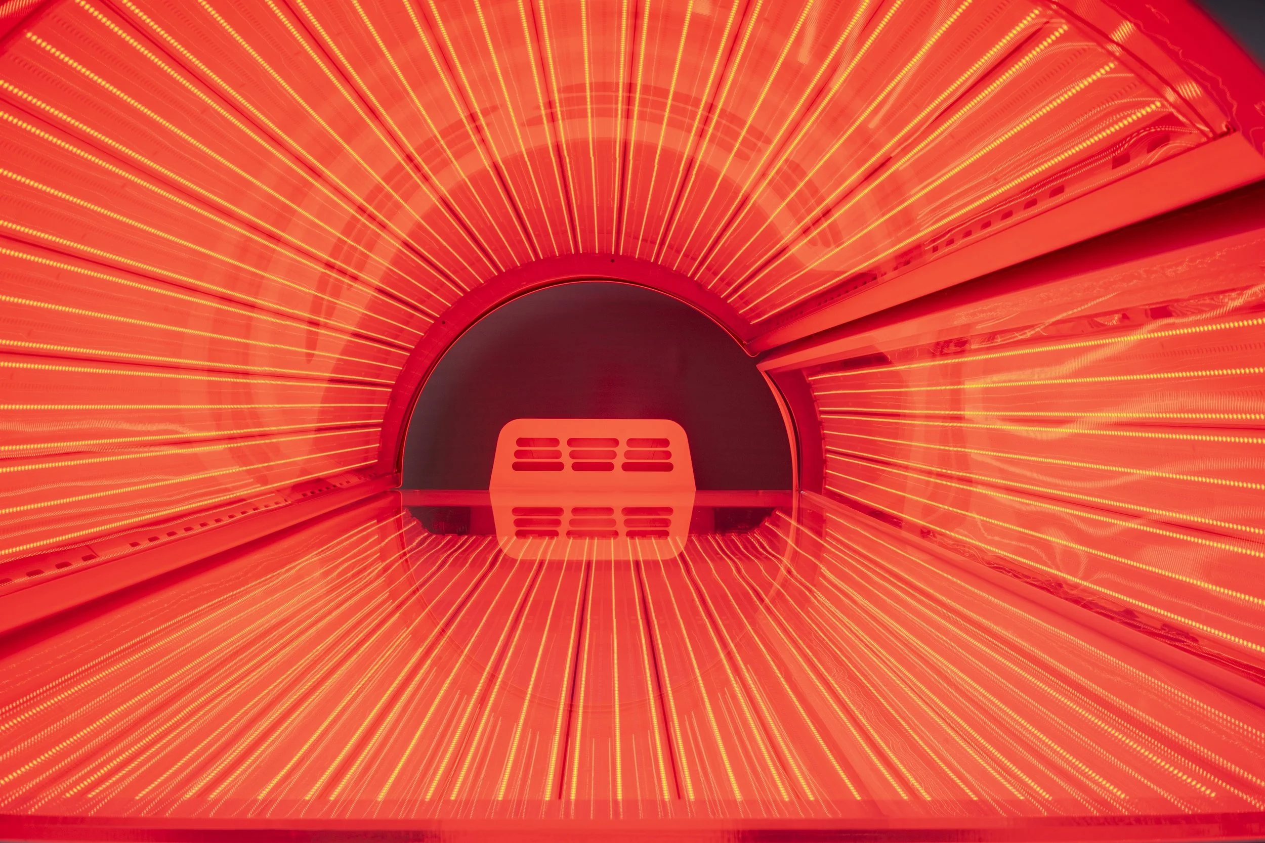 Close-up view of a red and orange LED light therapy device with a circular opening and illuminated light strips radiating outward.