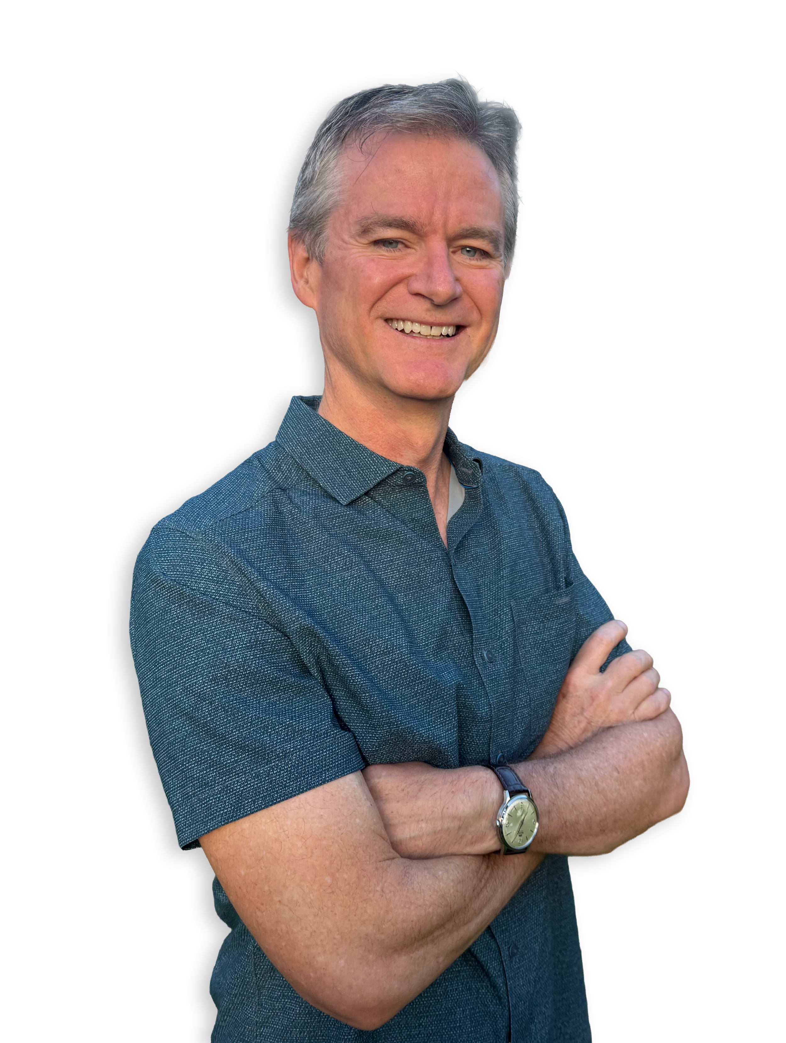 A smiling middle-aged man with gray hair, wearing a blue short-sleeved button-up shirt, standing with his arms crossed, against a black background.
