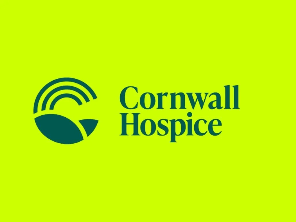 Logo of Cornwall Hospice with a green background, a circular emblem with a rainbow arch, a leaf, and a petal design.