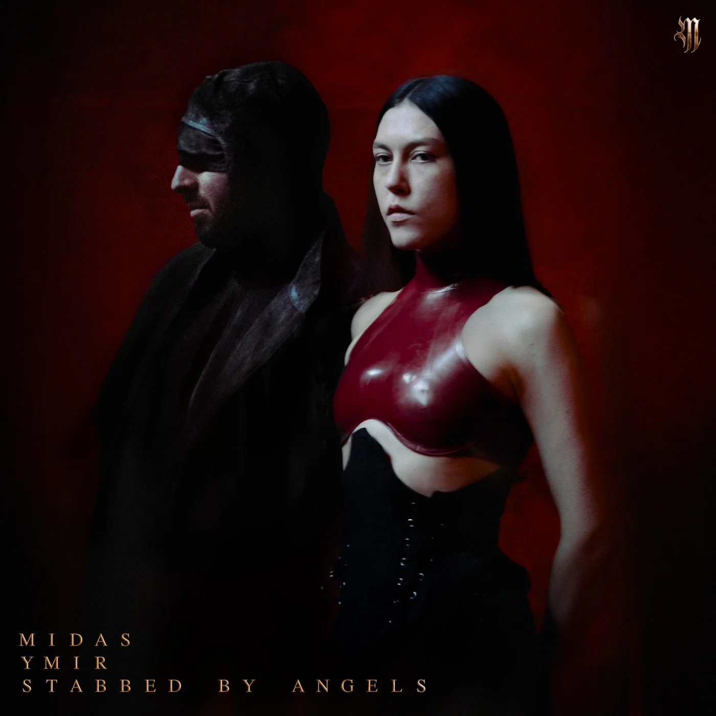 A man and a woman standing side by side against a dark red background. The man has dark hair and is wearing dark clothing, with his face turned in profile and eyes closed. The woman has long dark hair and is wearing a shiny red and black top with a s
