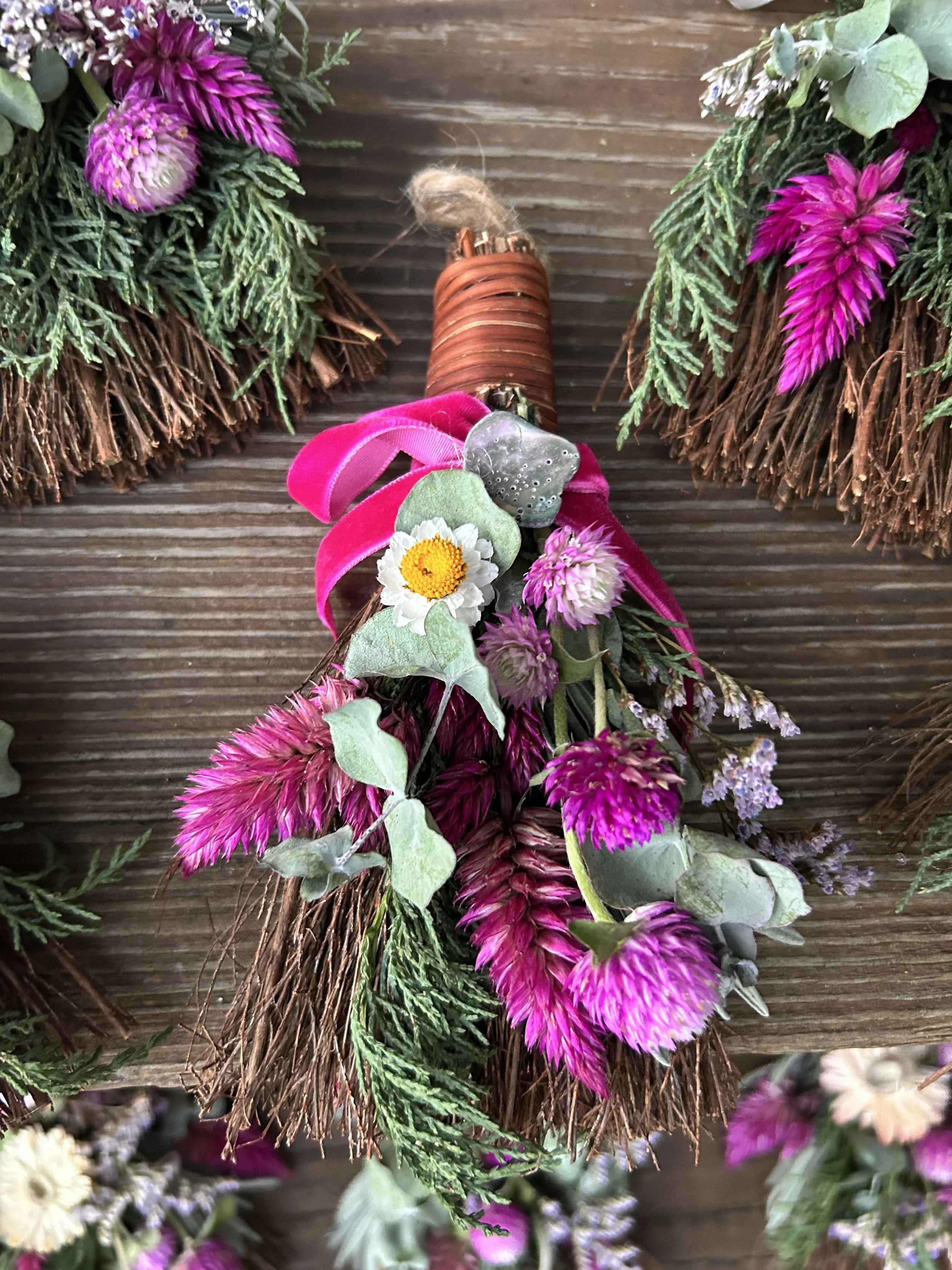 Flower arrangement with pink, purple, white, and green flowers and greenery on a wooden surface.