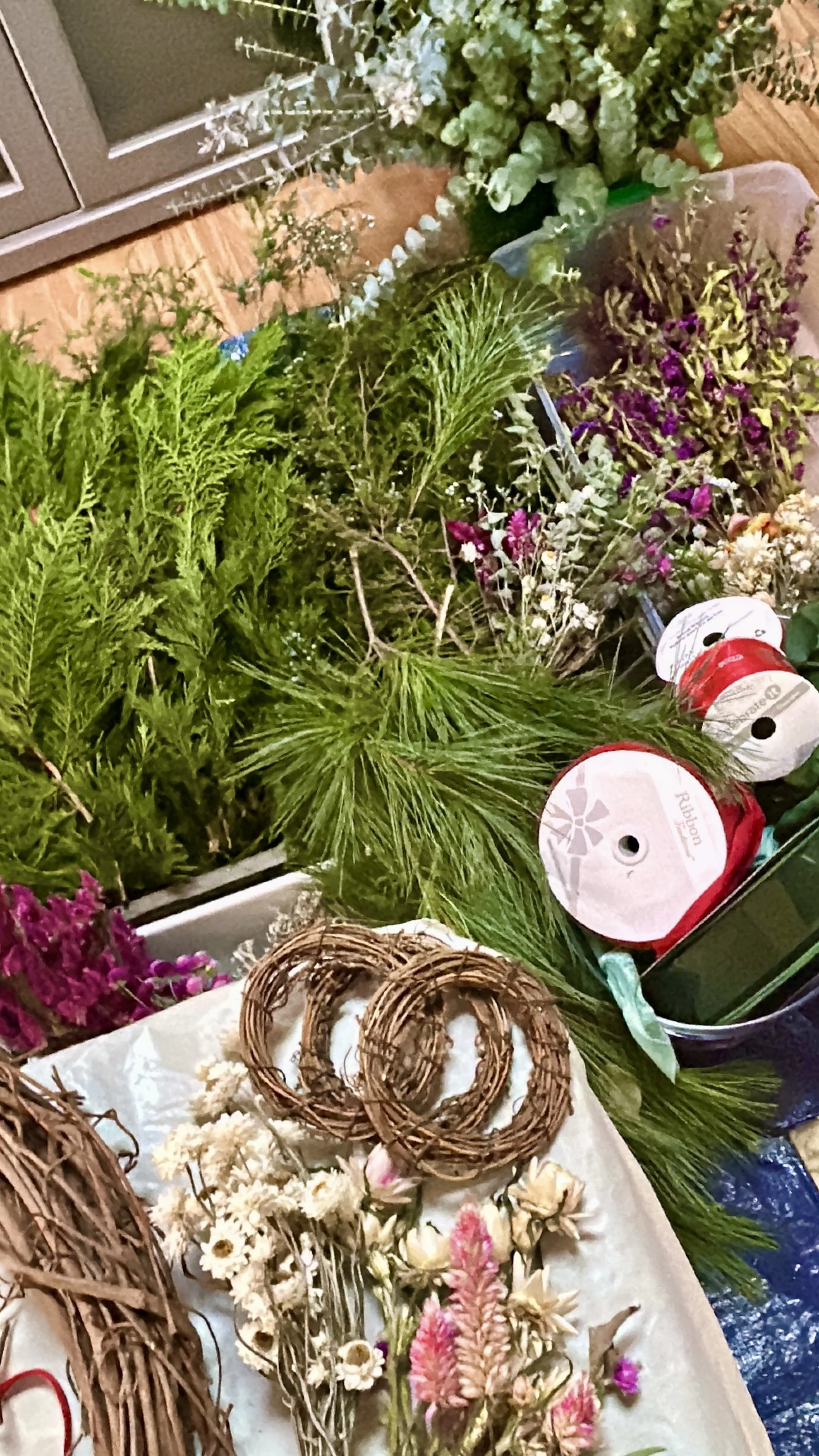 Assorted decorative flowers, greenery, and woven wreaths arranged on a display table, likely for crafting or decoration purposes.
