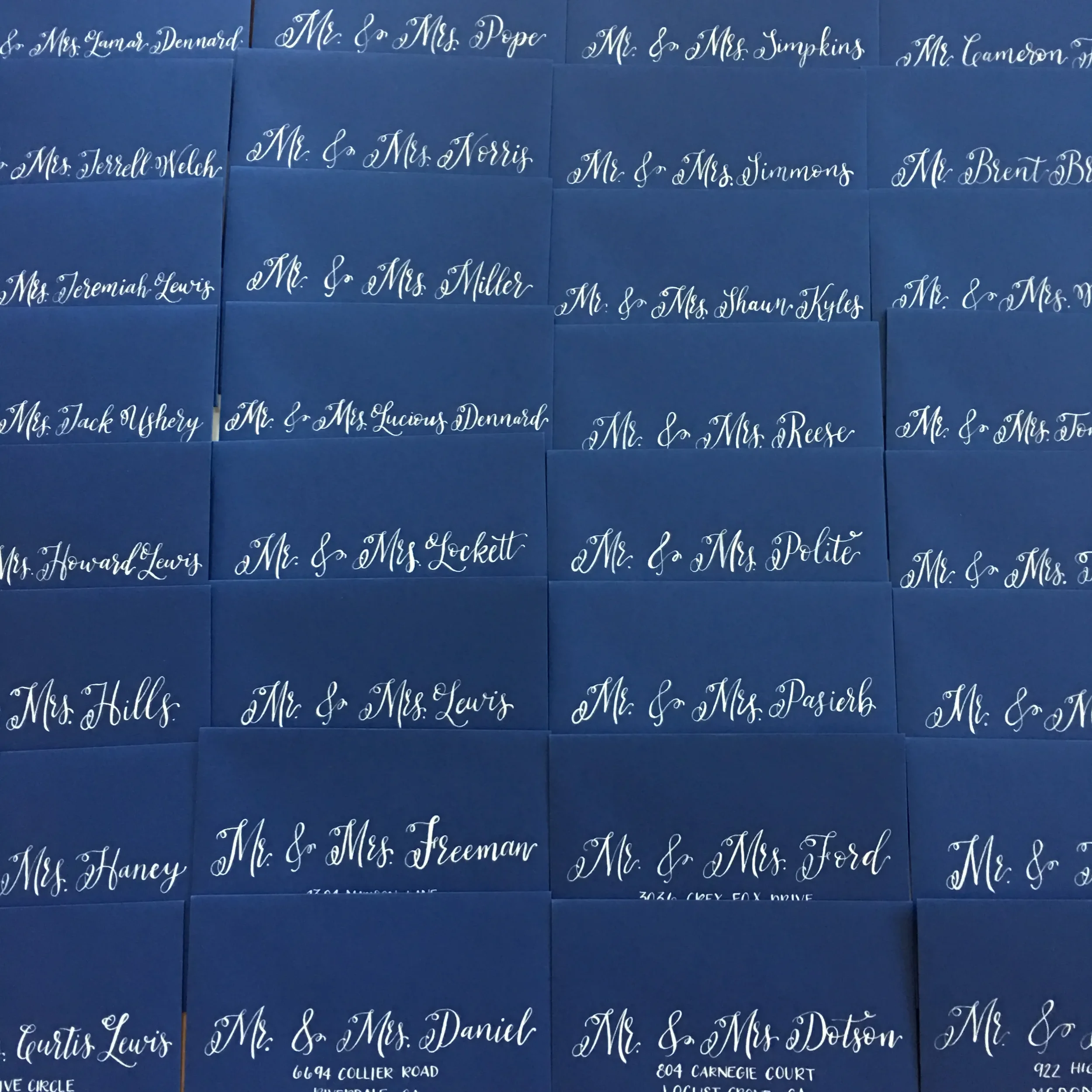 Crisp white ink calligraphy guest addressing on a dark navy blue mailing envelopes.