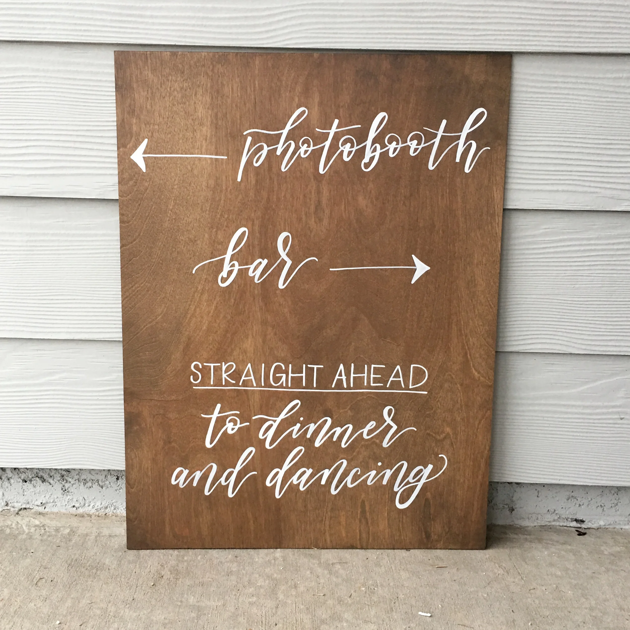 Custom arrow directional sign for wedding reception in white hand-lettering.
