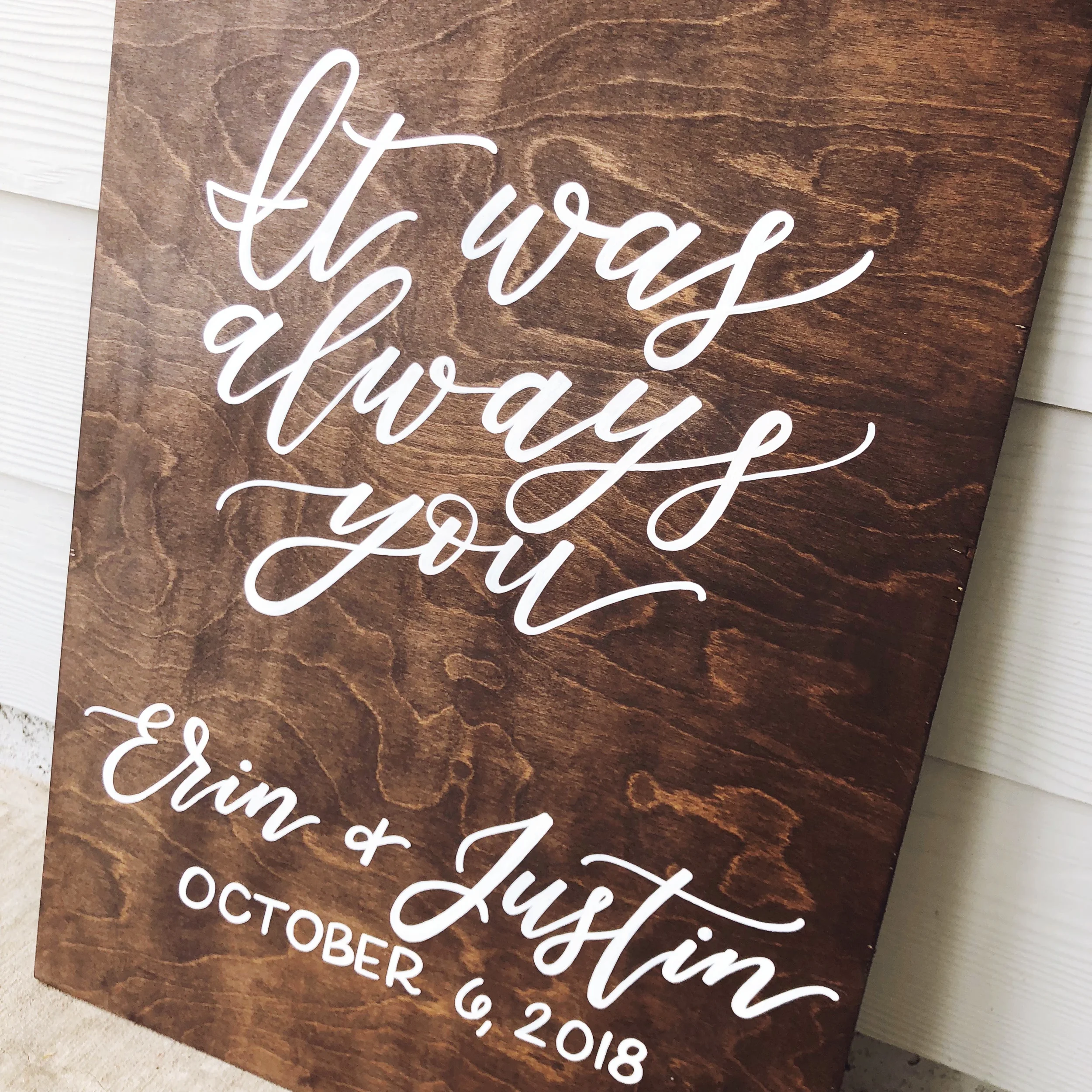 Capture timeless romance with an "It Was Always You" hand-lettered wooden quote board. Written in sweeping white cursive over a rich dark stained wood panel, this personalized sign brings cozy, modern-rustic charm to your photo displays or dessert ta