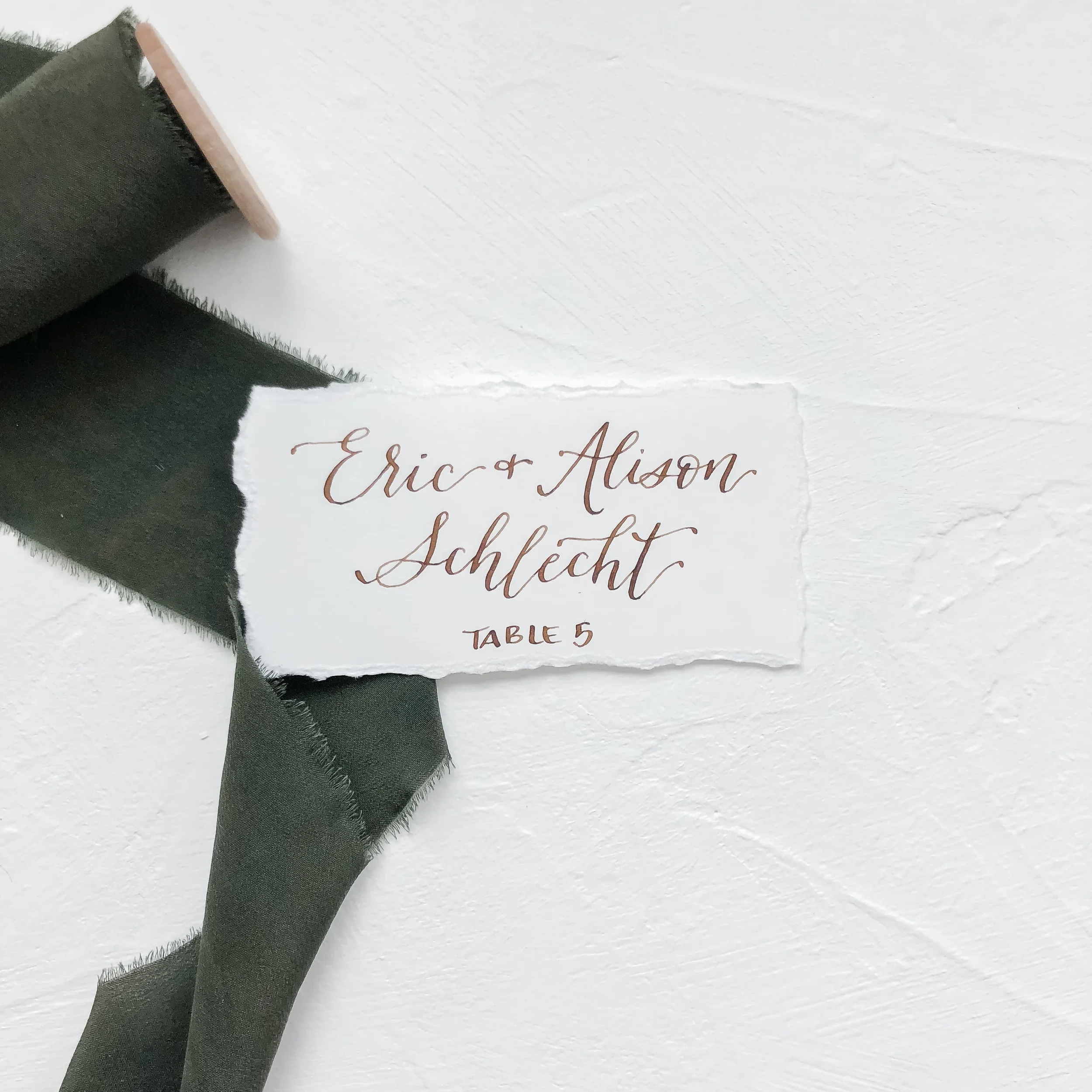White torn edge escort card with walnut brown calligraphy ink.