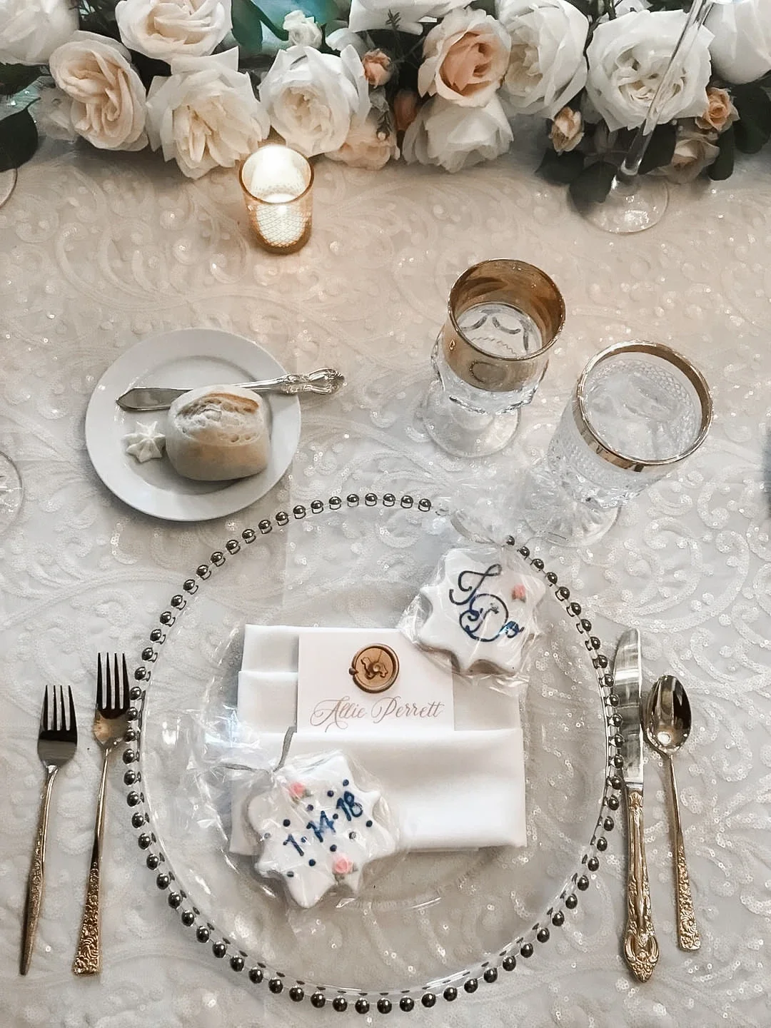 Glamorous silver and white wedding place setting with delicate script calligraphy name card and candles.