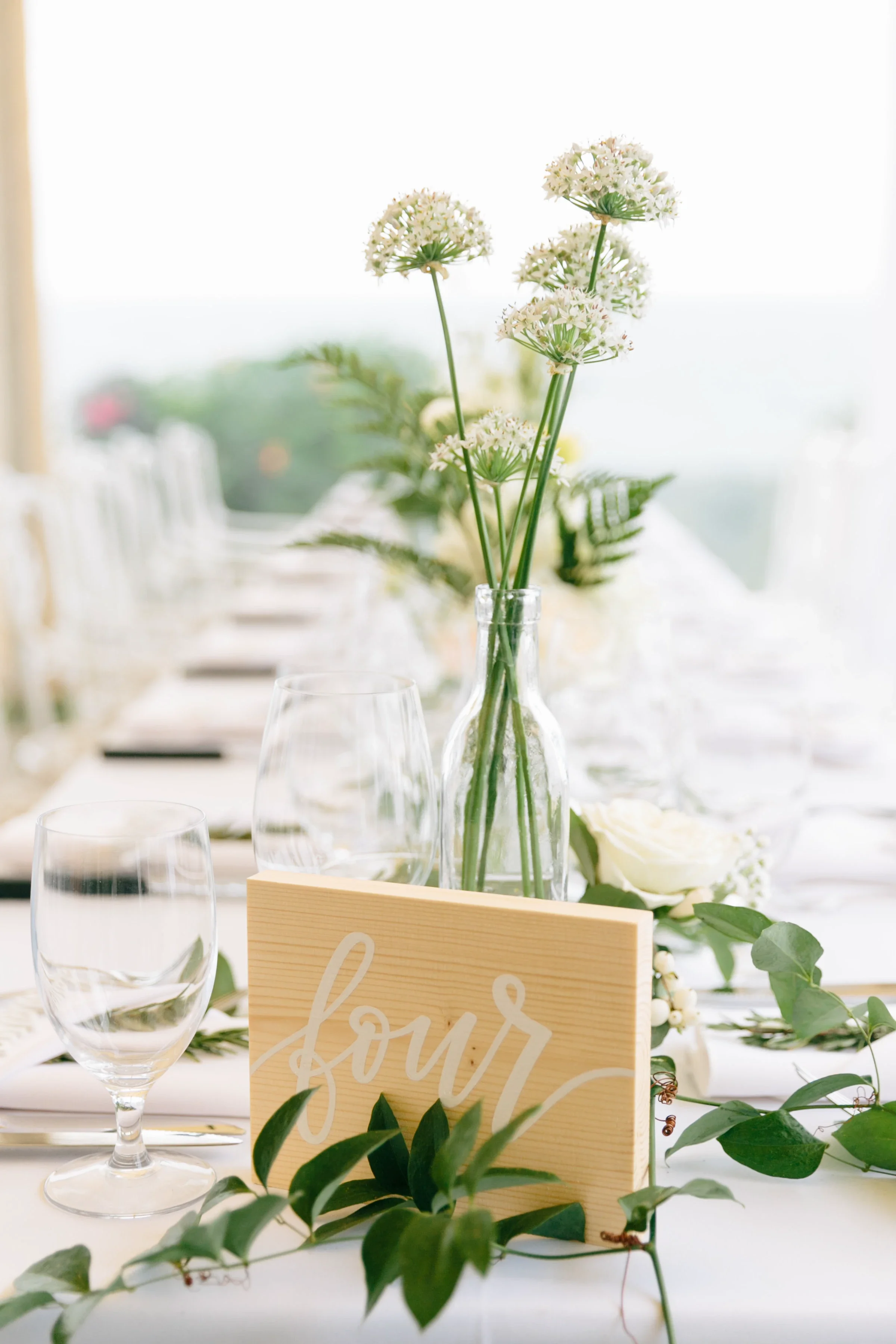 Natural wood block table number with white script hand-lettering.