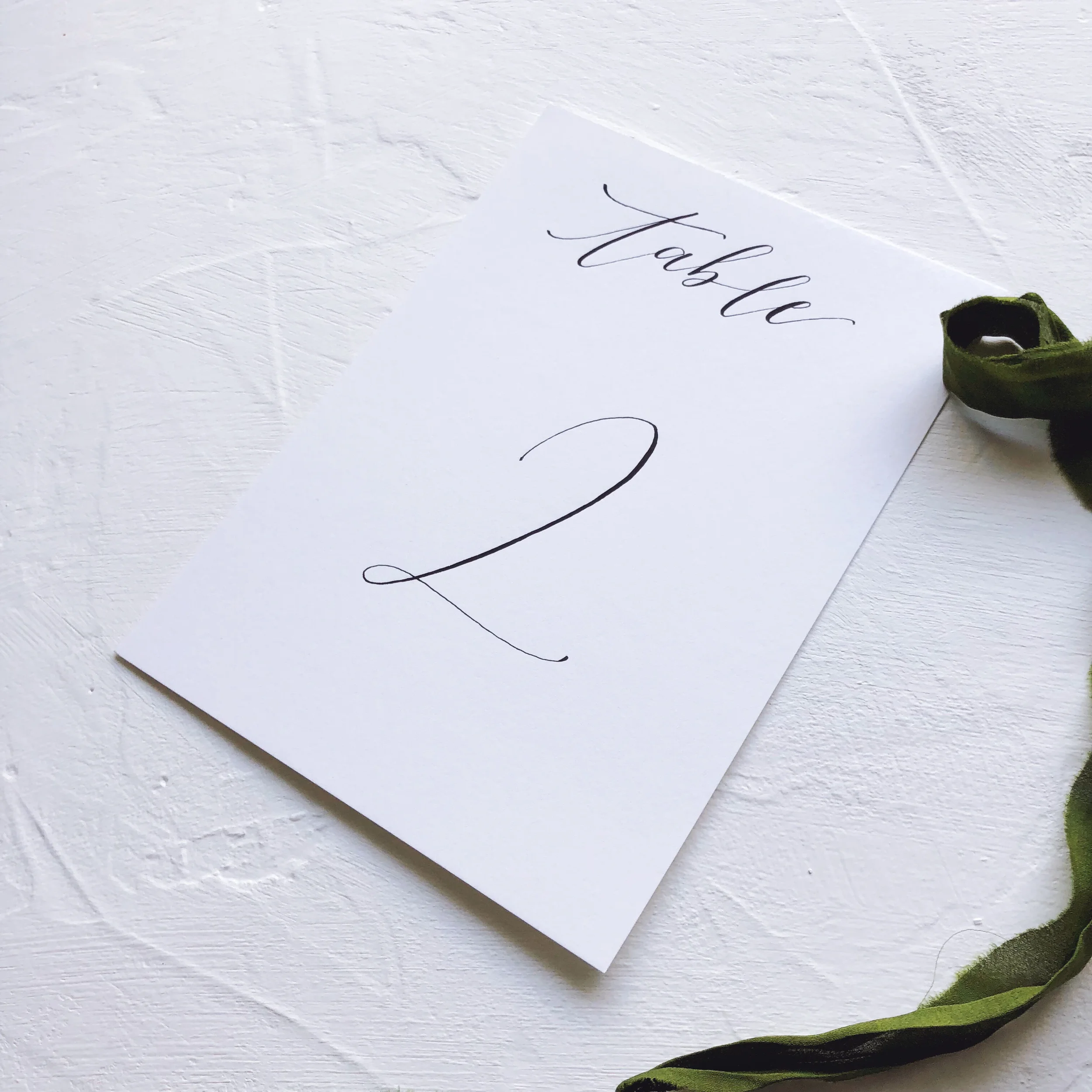 Elegant calligraphed wedding table numbers printed on clean white paper and black ink.