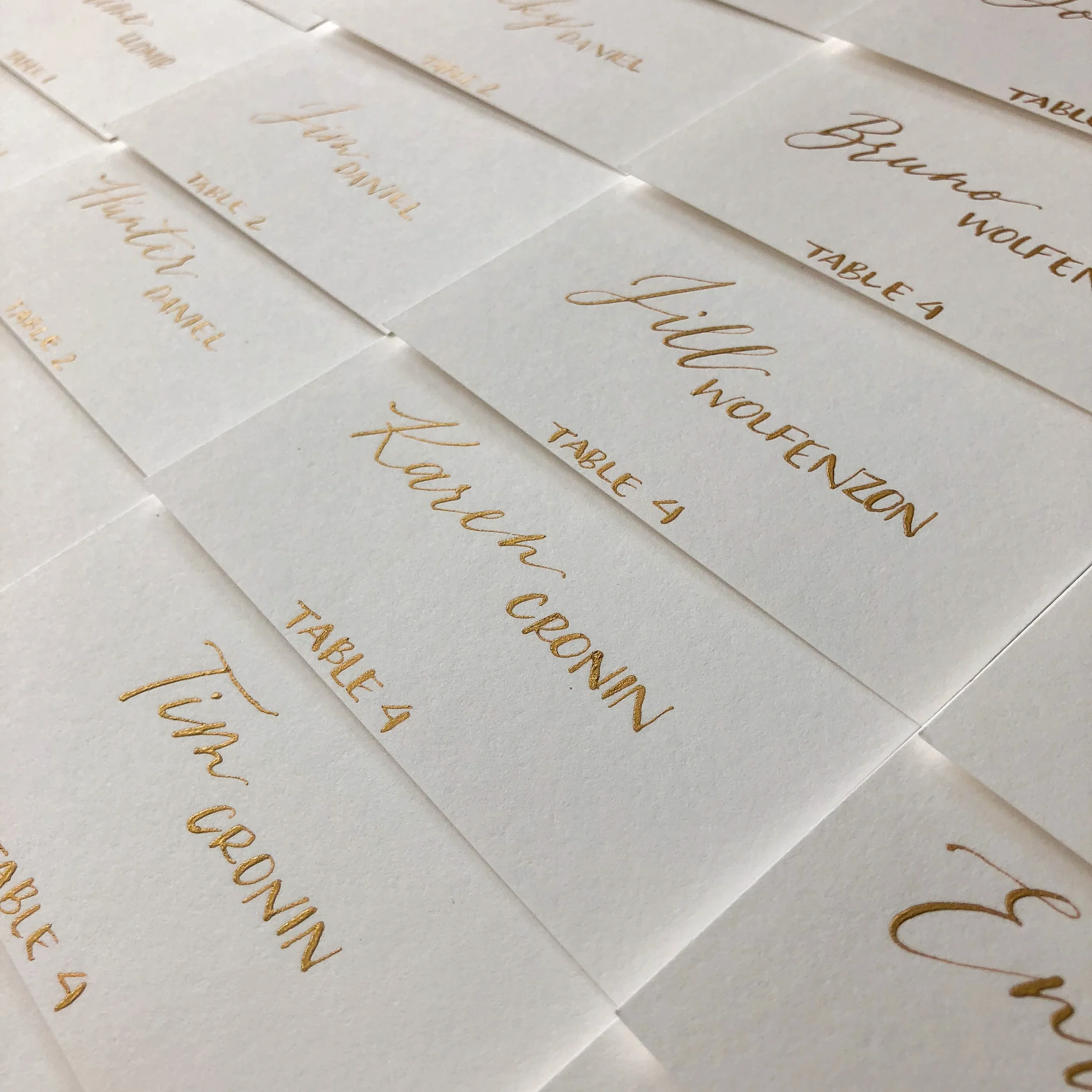 Mix font calligraphy in gold ink on white paper escort cards.