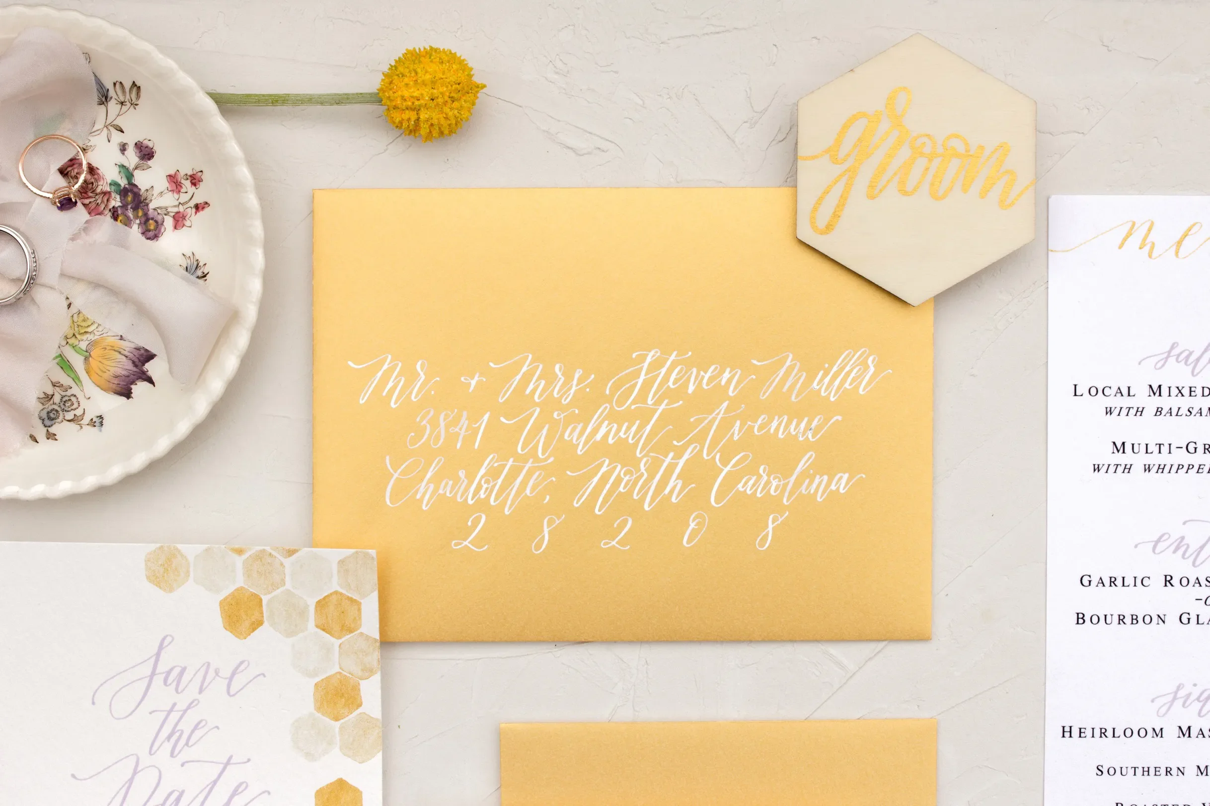 Gold yellow wedding invitation details including a custom hexagon wood "groom" place card.