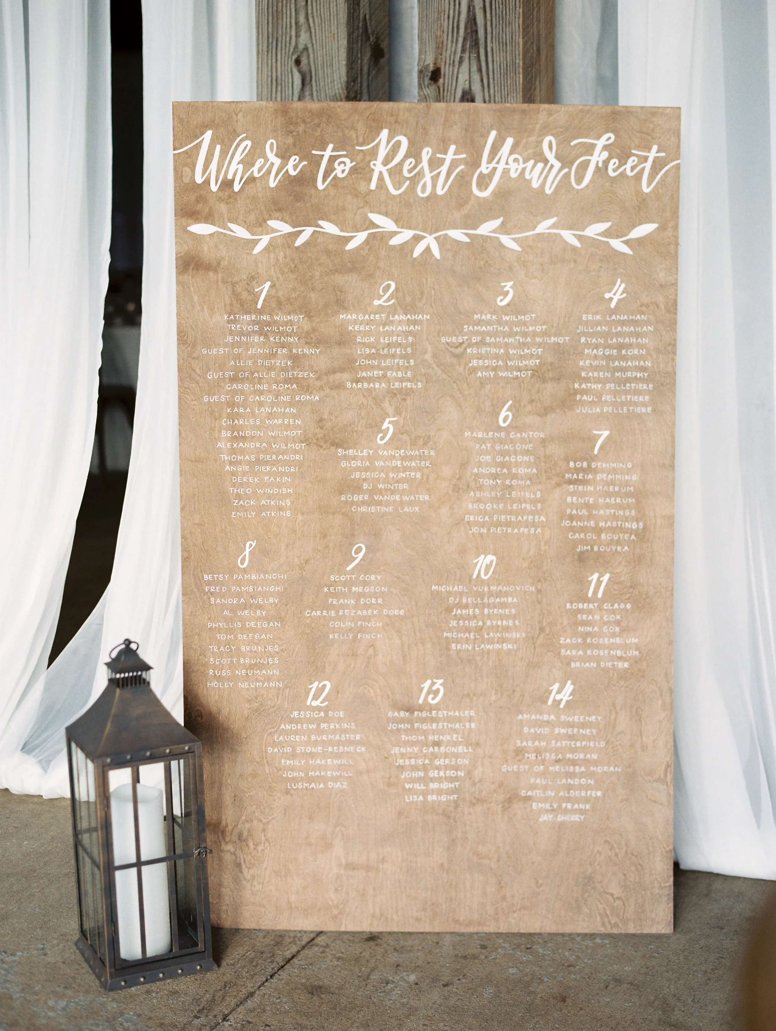 Tall light-wood panel seating chart titled "Where to Rest Your Feet" with white calligraphy table lists.