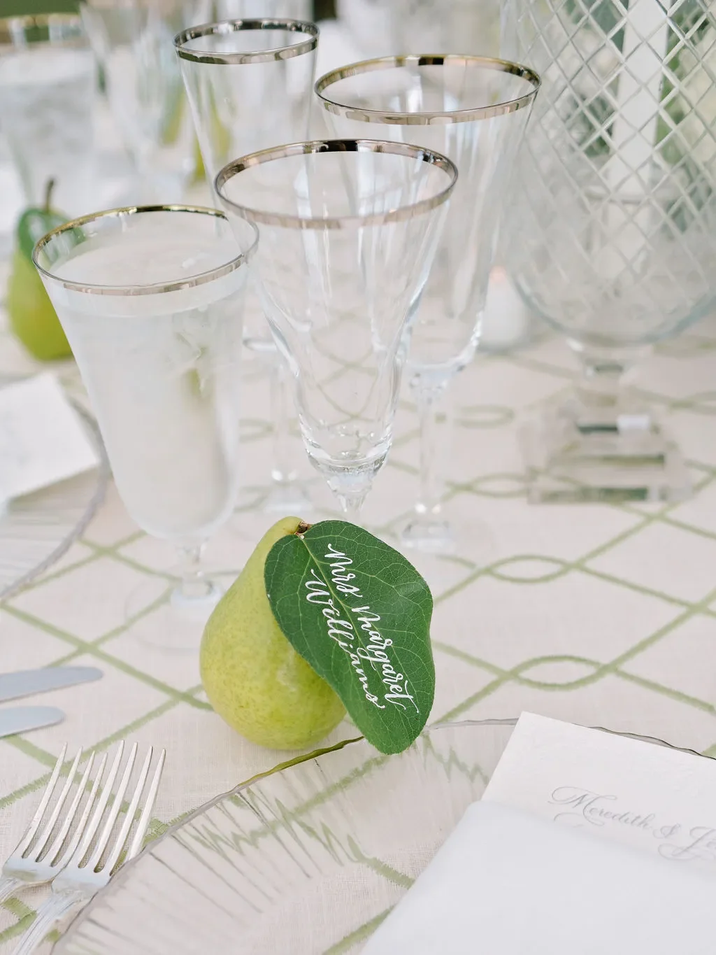 Hand-lettered pear escort card complements a romantic garden-inspired wedding tablescape featuring lush florals, candlelight, and timeless reception details.